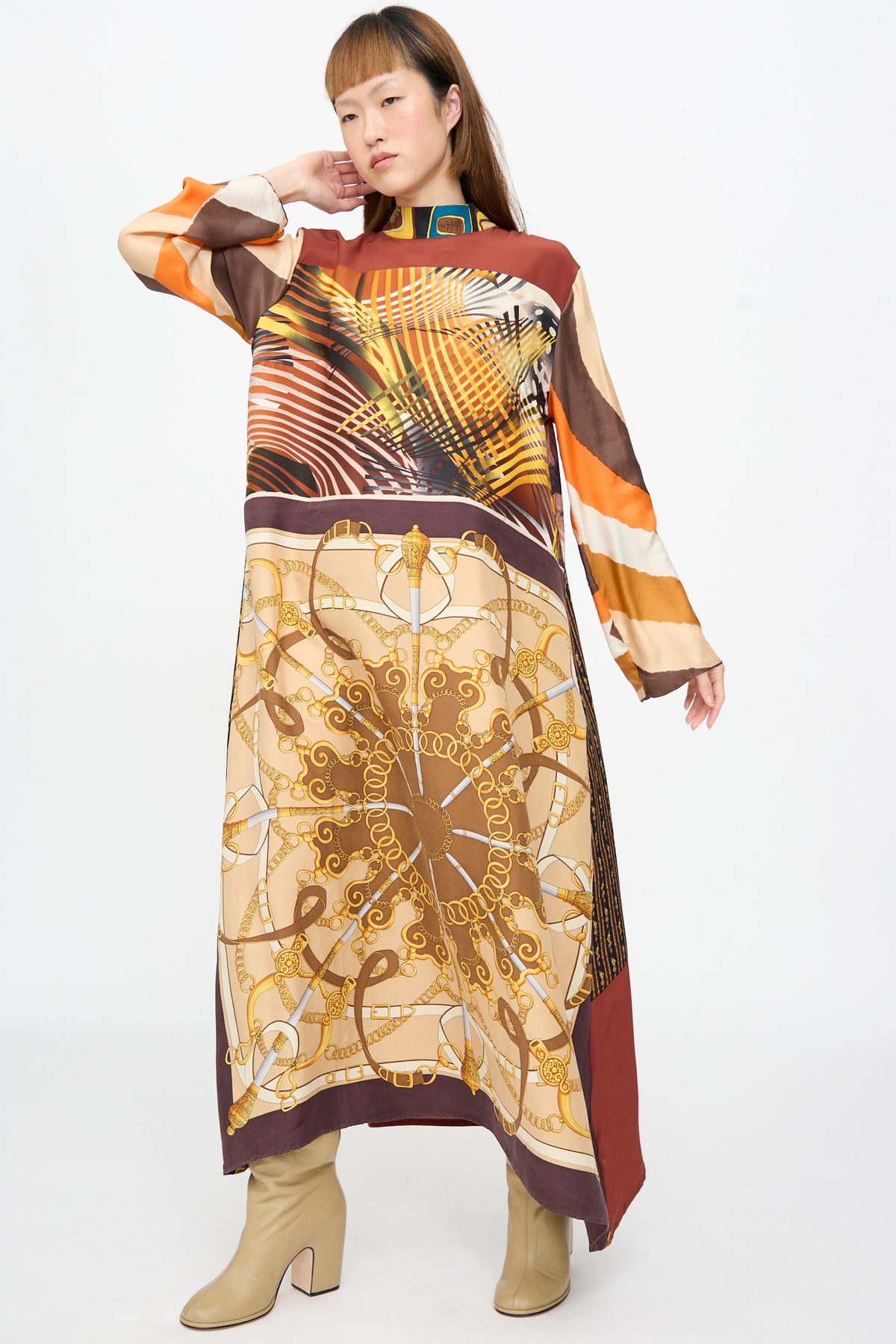 A person wears a Bettina Bakdal Classic Mandarin Collar Dress in Benita Otte, a long-sleeved, knee-length up-cycled silk dress with a geometric print, styled with beige block-heel boots.