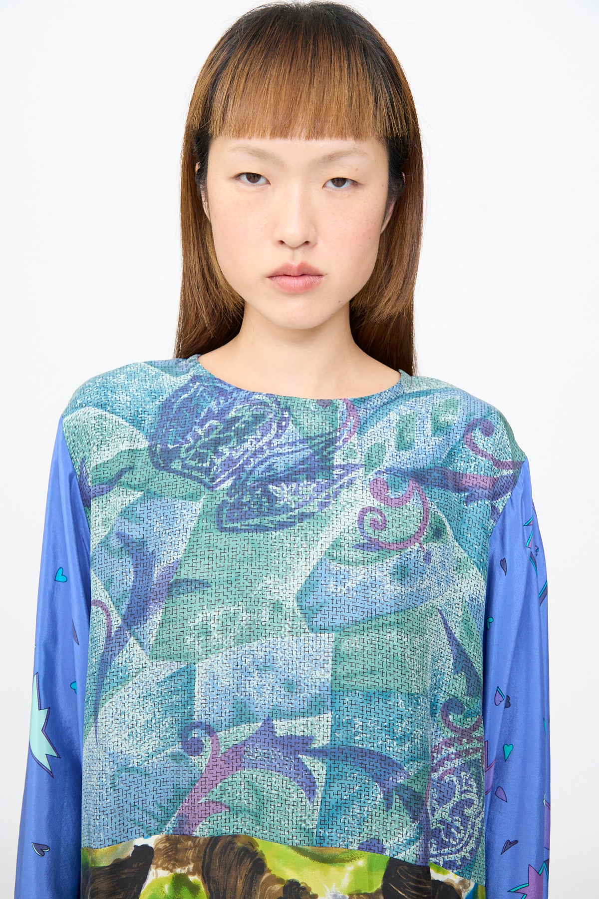 The Bettina Bakdal Hannah Dress in Lucia Moholy is an up-cycled silk dress with a multi-colored geometric bodice and blue sleeves featuring small heart and star motifs.