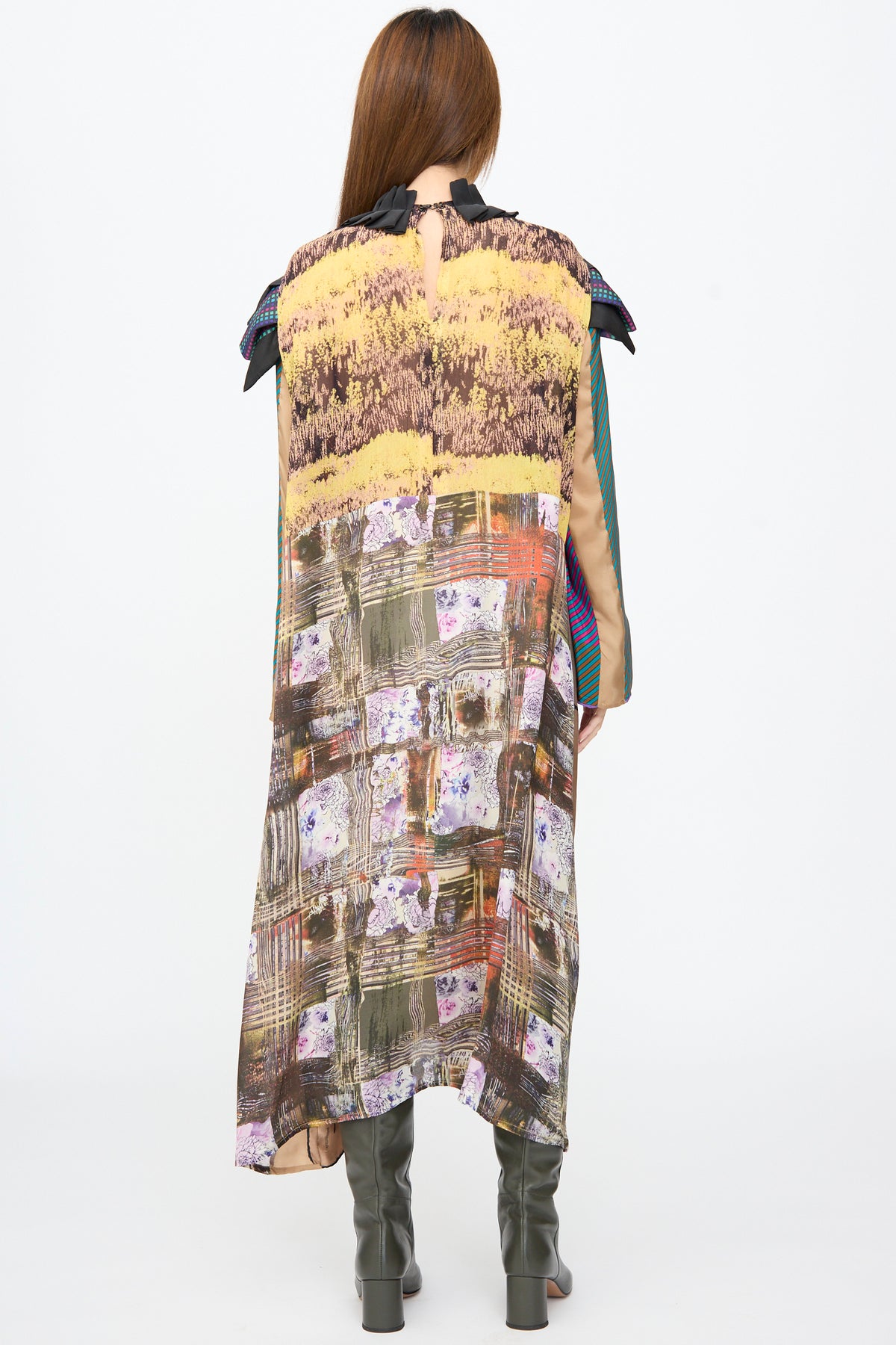 Back view of the Bettina Bakdal Ruffled Collar and Shoulder Dress in Marguerite Friedlaender, a sleeveless up-cycled silk piece with a dark ruffled collar and multicolored patchwork, worn over dark boots.
