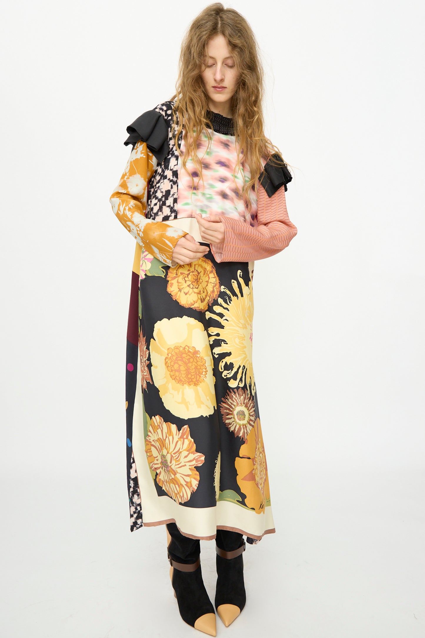 A person with long, wavy hair wears the Bettina Bakdal Ruffled Collar and Shoulder Vintage Scarves Dress in Edith Suschitzky with black boots, standing against a plain white background.