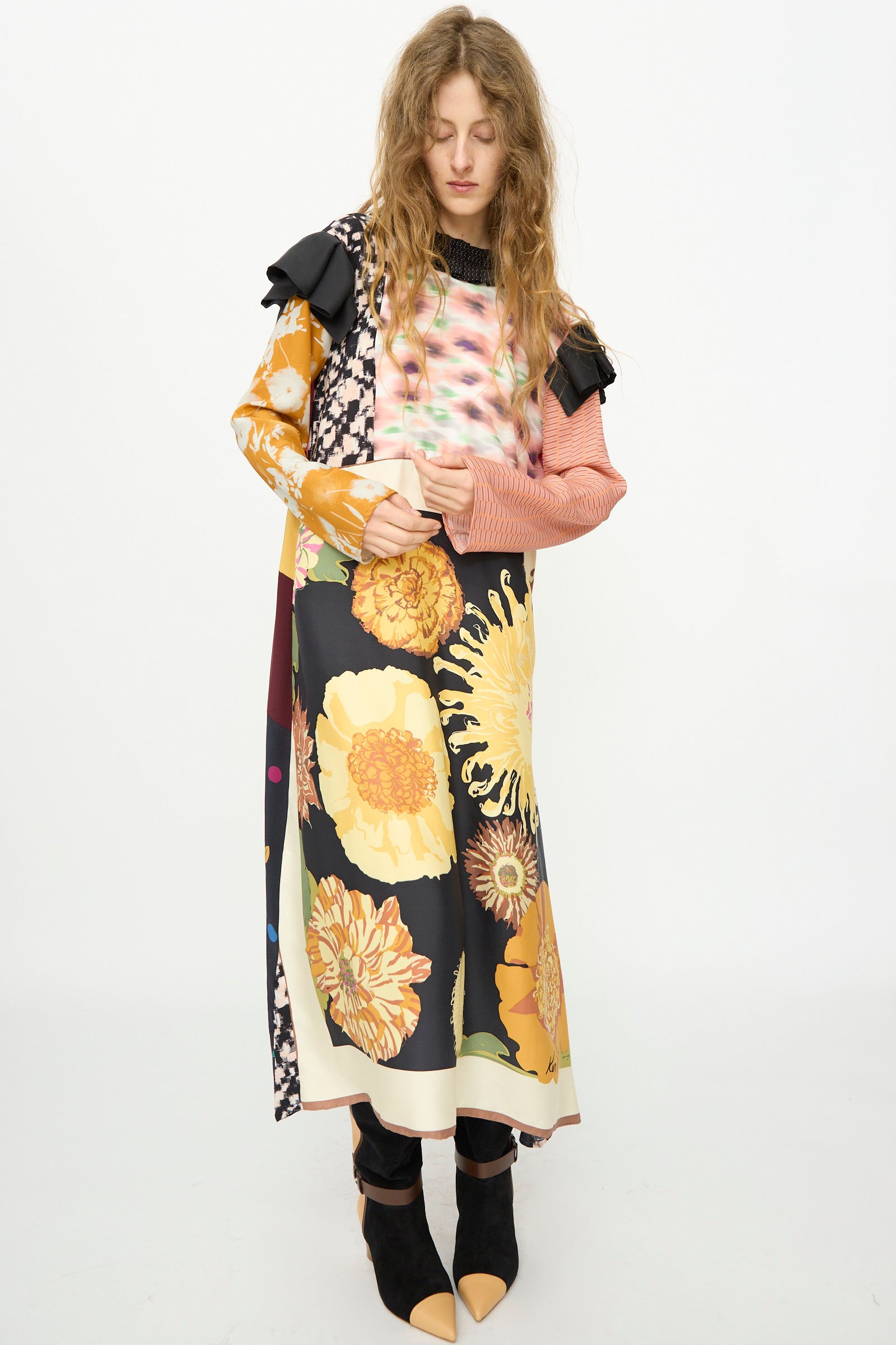 A person with long, wavy hair wears the Bettina Bakdal Ruffled Collar and Shoulder Vintage Scarves Dress in Edith Suschitzky with black boots, standing against a plain white background.