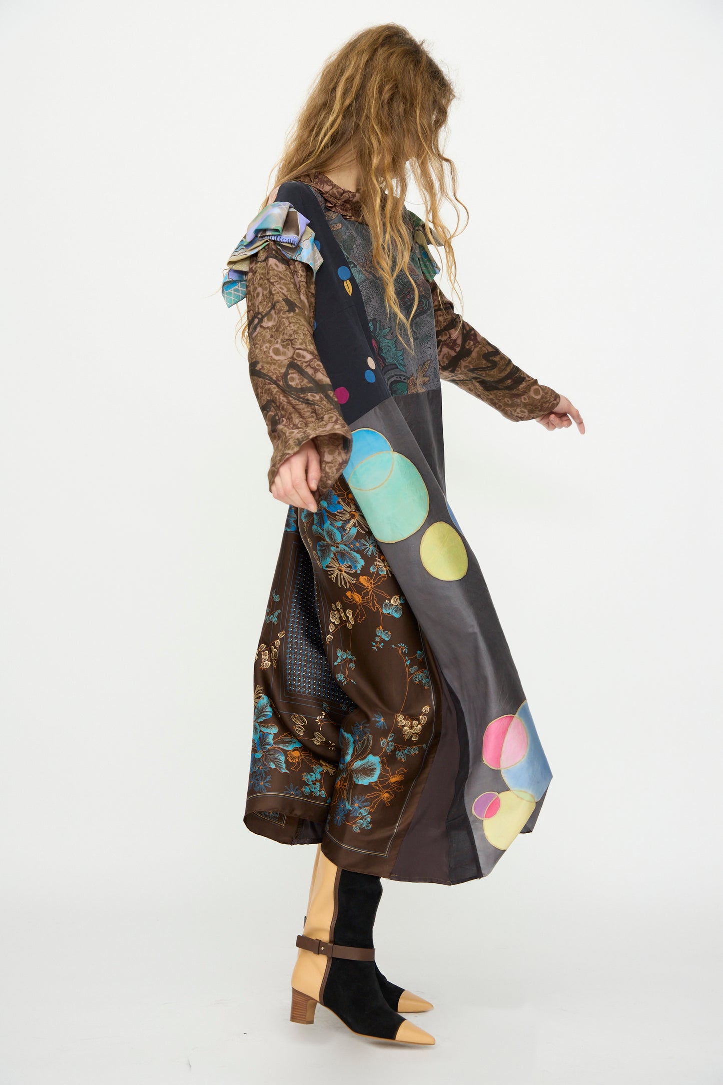 A person wears the Bettina Bakdal Ruffled Collar and Shoulder Vintage Scarves Dress in Margarete Dambeck, featuring colorful circles and florals, with black socks and tan heels against a white background for a unique vintage flair.