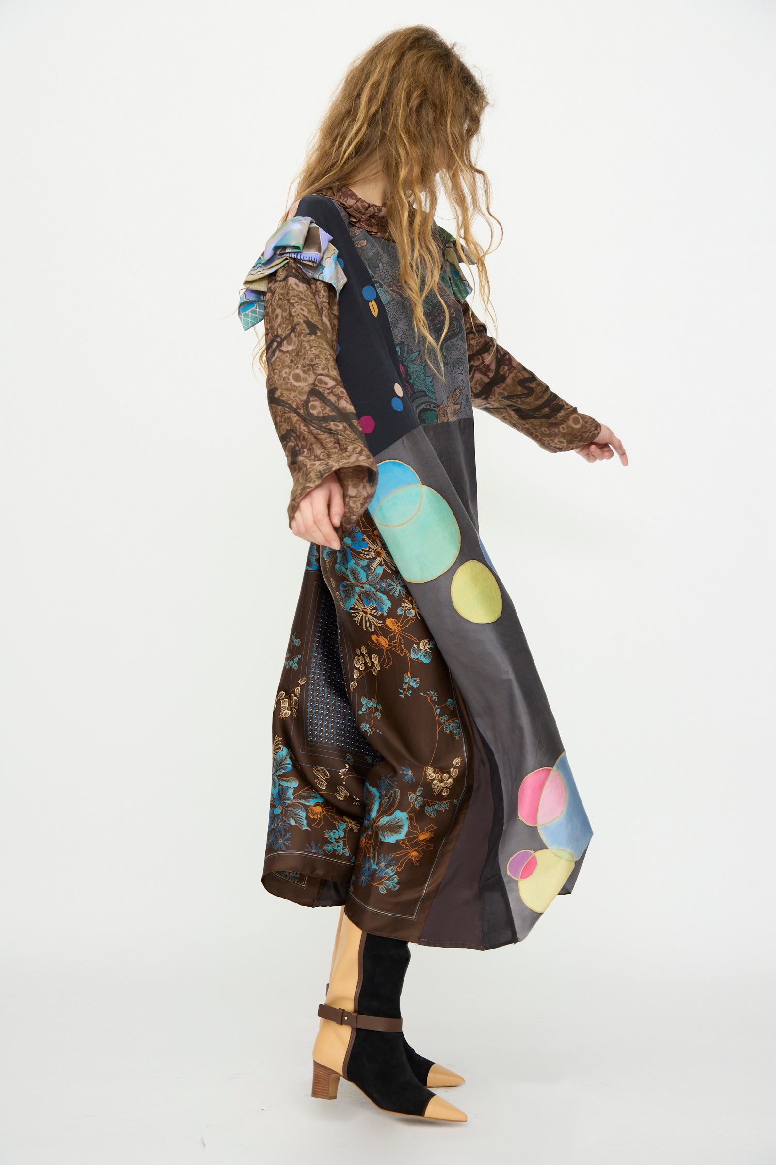 A person wears the Bettina Bakdal Ruffled Collar and Shoulder Vintage Scarves Dress in Margarete Dambeck, featuring colorful circles and florals, with black socks and tan heels against a white background for a unique vintage flair.