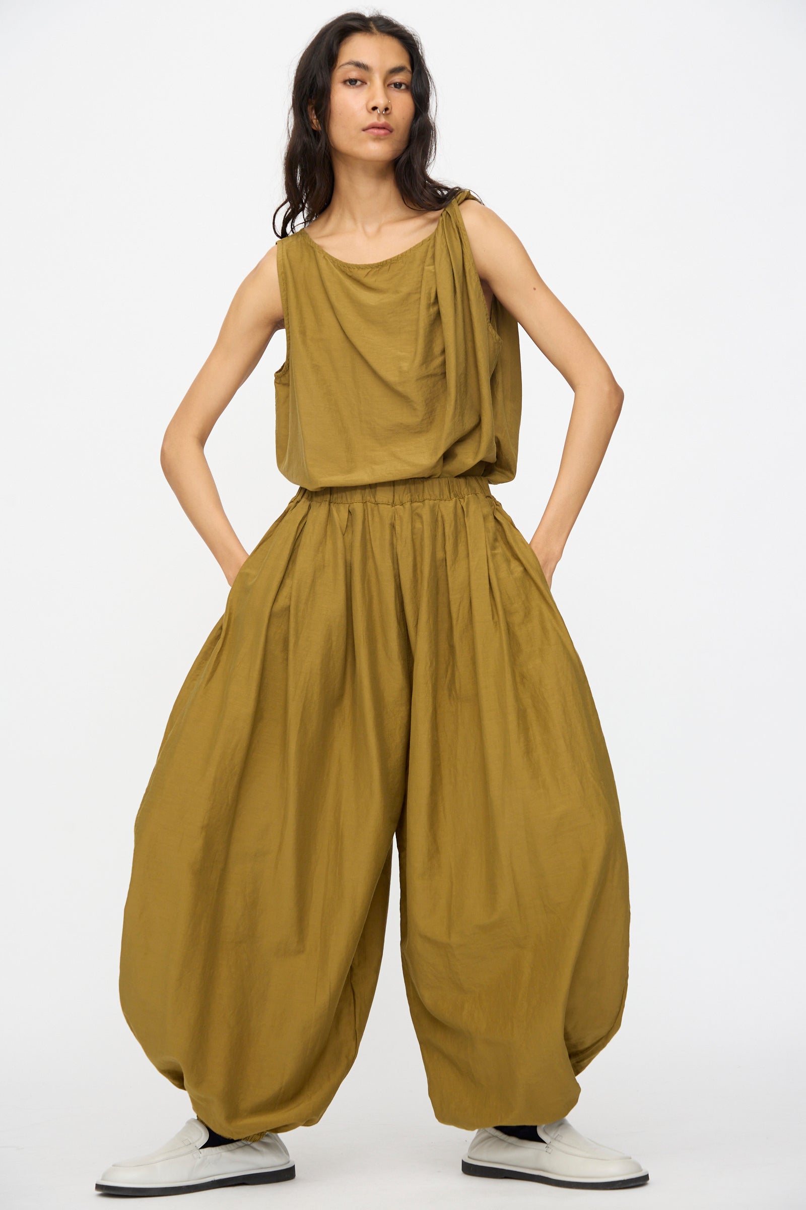 Person wearing Black Crane Akari Pants in Dark Olive, relaxed fit balloon style with hands in pockets, standing against a plain white background.