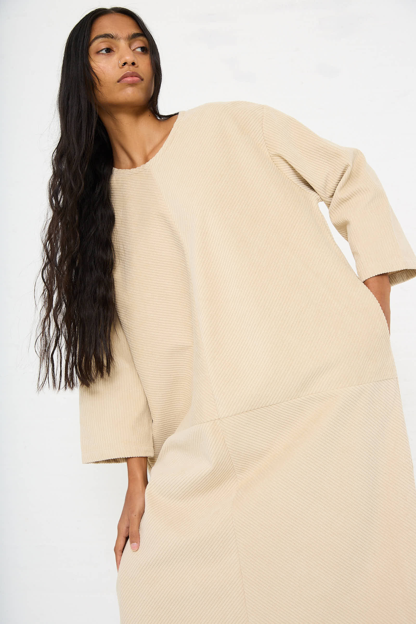 Person with long hair wearing a loose Cotton Corduroy Radient Dress in Ivory by Black Crane poses against a plain background.