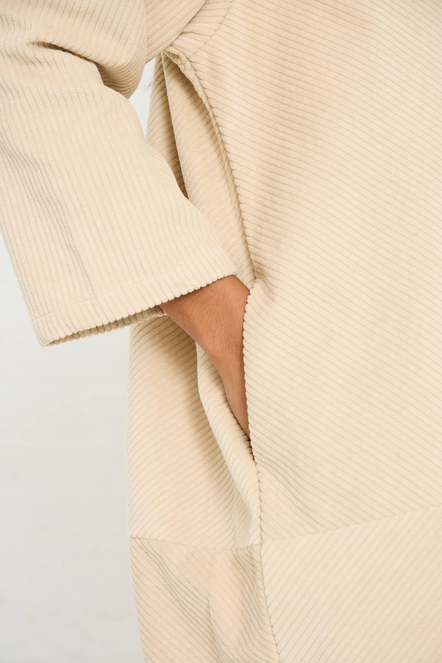 Close-up of a person wearing the Black Crane Cotton Corduroy Radient Dress in Ivory with their hand in the pocket.