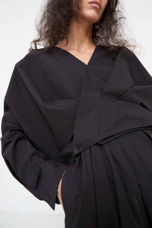 A woman wearing an Organic Cotton Cross Shirt in Black by Los Angeles-based label Black Crane, with structural folds against a white background.
