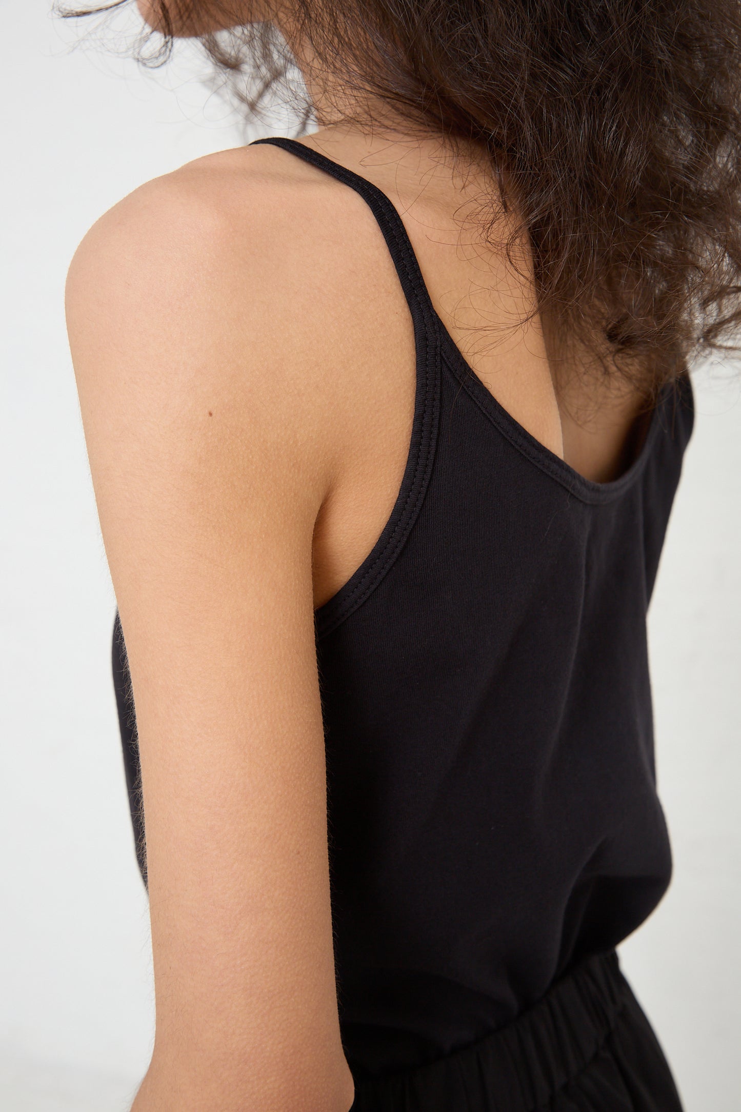 Woman wearing a Black Crane organic Cotton Jersey Camisole in Black, seen from behind at a slightly angled view.