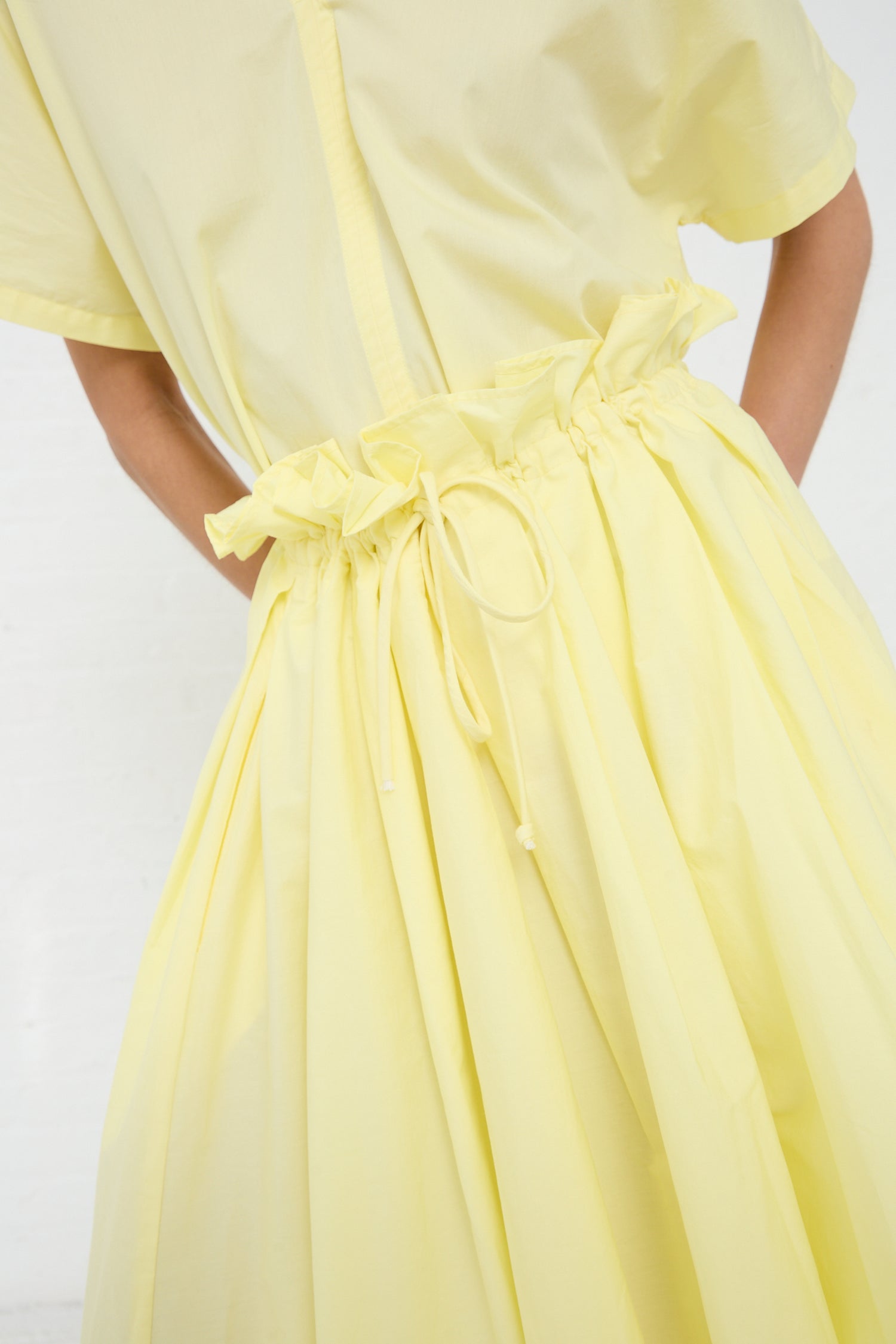 A person seen from the back wearing a Lemon Organic Cotton Parachute Skirt from Black Crane with a bow detail at the waist.