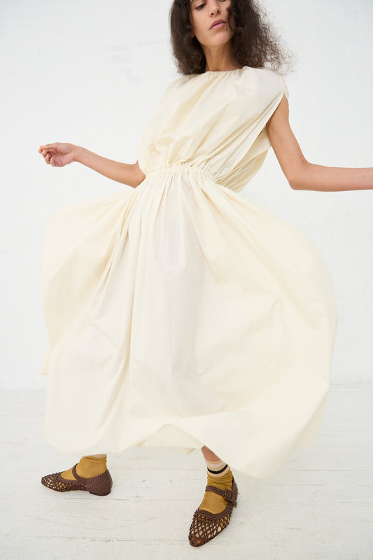 A person in a flowing Black Crane Organic Cotton Shell Dress in Cream and brown woven shoes standing against a white background.