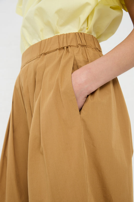 Woman with hand in pocket of a Black Crane Organic Cotton Straight Draped Pant in Camel.