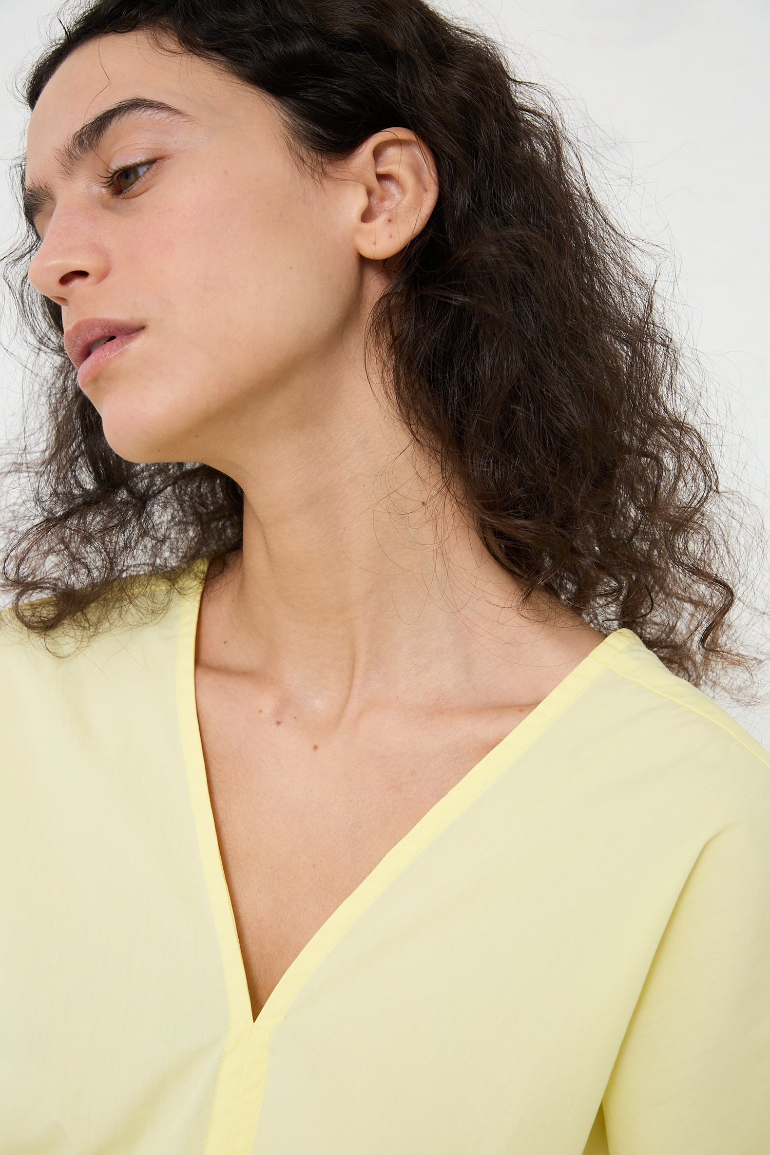 Woman in a Los Angeles fashion-inspired Black Crane Organic Cotton V-Neck Top in Lemon, viewed in profile.