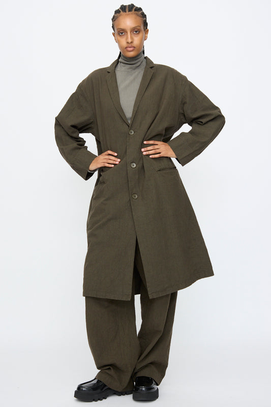 Person wearing the Black Crane Crinkled Coat in Charcoal with matching wide-leg pants, a gray turtleneck, and black shoes, standing against a plain white background.
