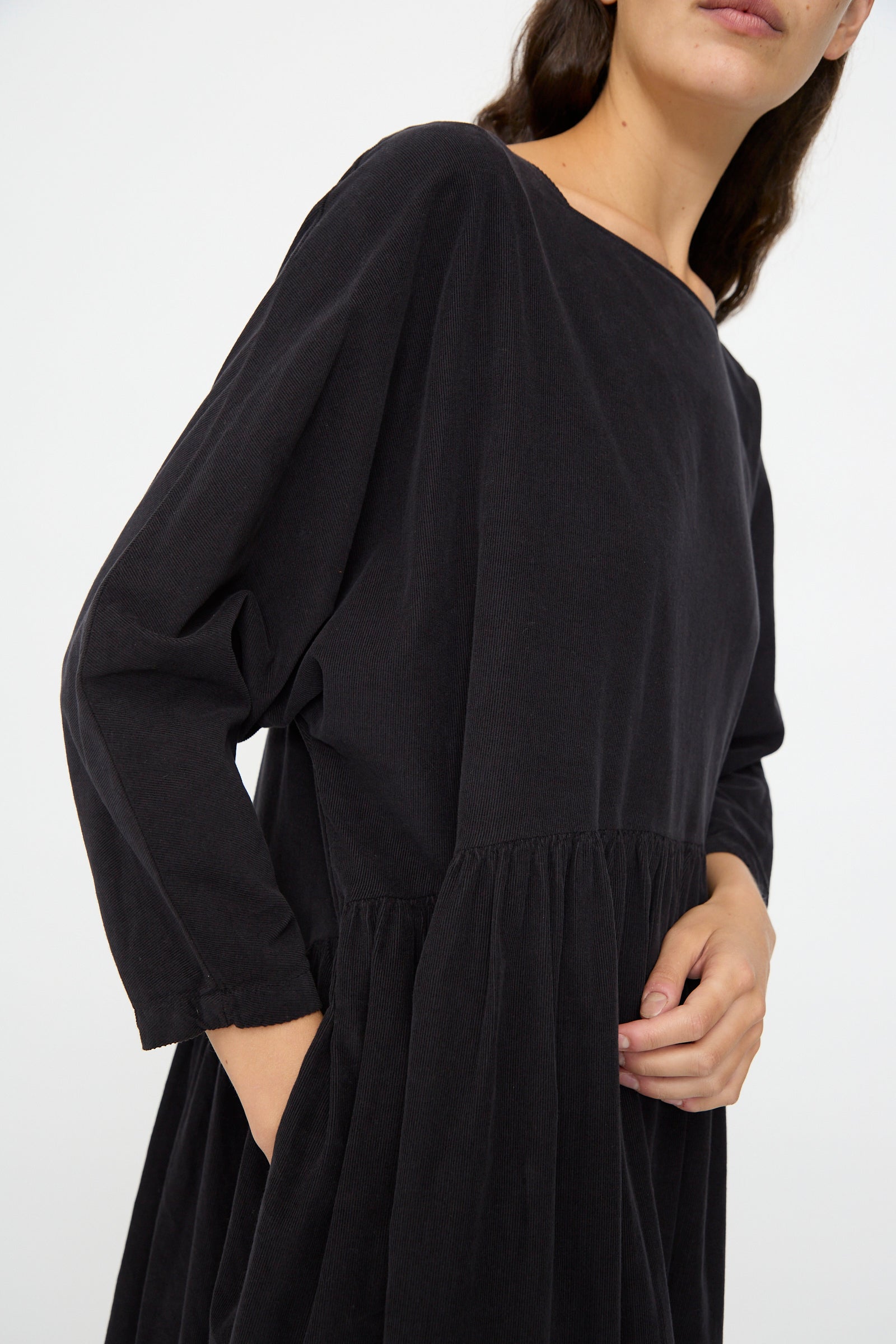 A person wearing the Black Crane Tradi Dress in Dark Navy, featuring an oversized fit, long sleeves, and a gathered waist, poses against a plain light background.