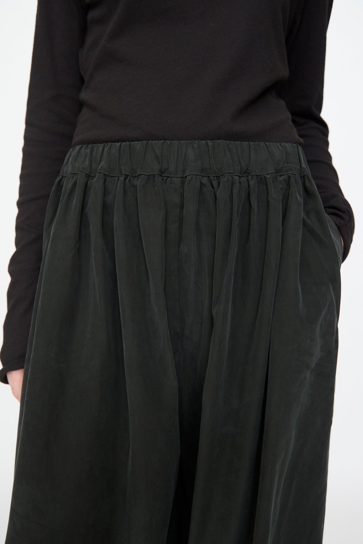 A person wearing the Black Crane Lantern Pants in black; only their torso and upper legs are visible.