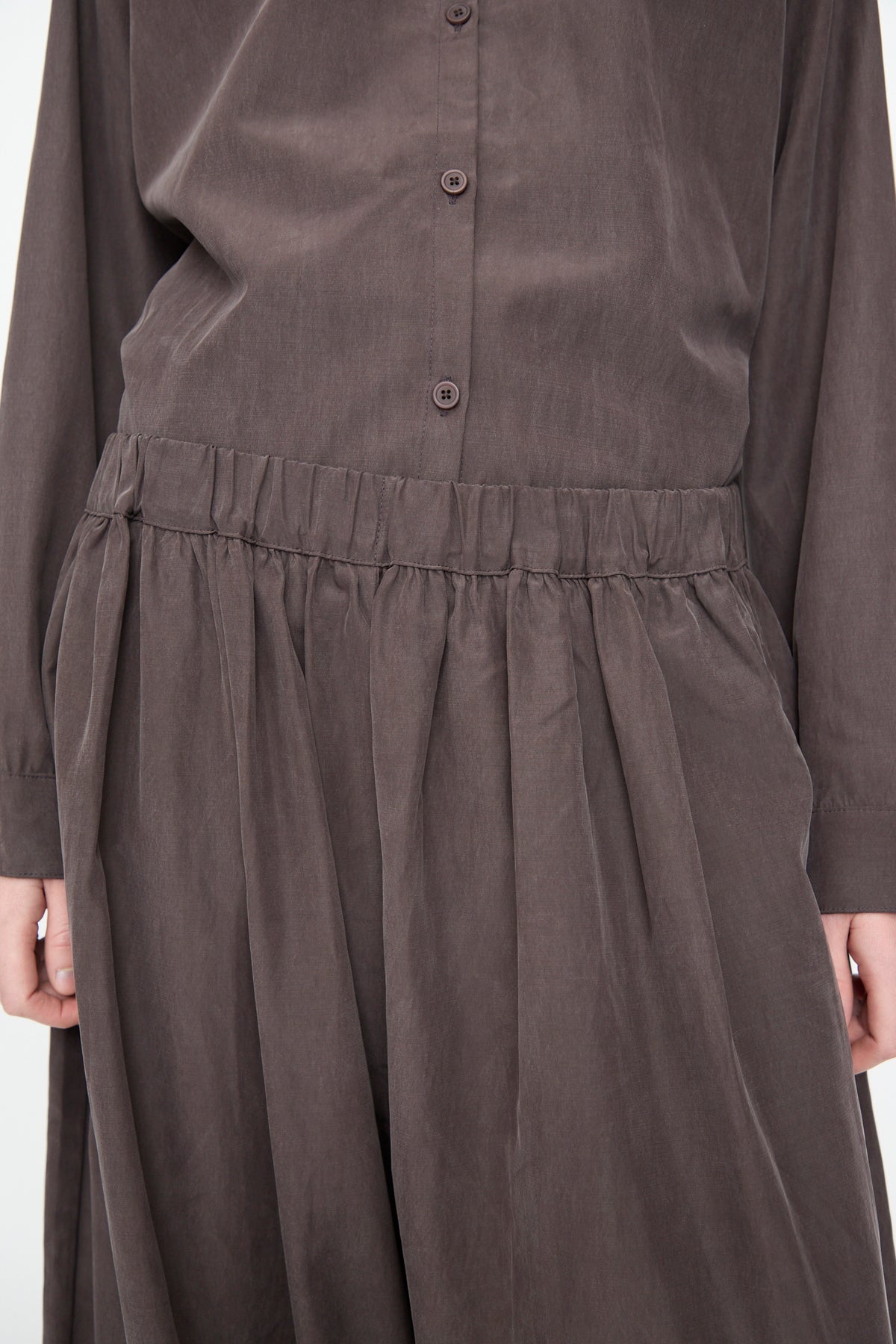 Close-up of a person wearing the Lantern Pants in Dark Plum by Black Crane, crafted from a soft cotton cupro blend for enhanced comfort and drape, featuring a loose fit and flowy silhouette.