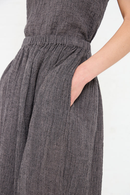 Close-up of a person wearing a Black Crane Linen Classic Skirt in Grey Navy with a cinched waist.