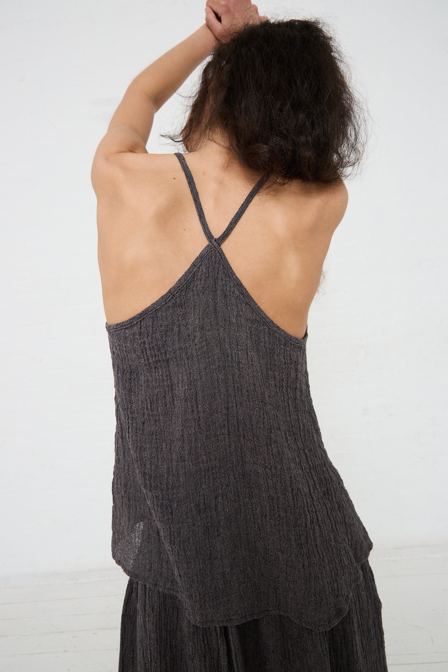 A woman seen from behind, wearing a sleeveless, Linen Textured Camisole in Grey Navy with crossed back straps by Black Crane.