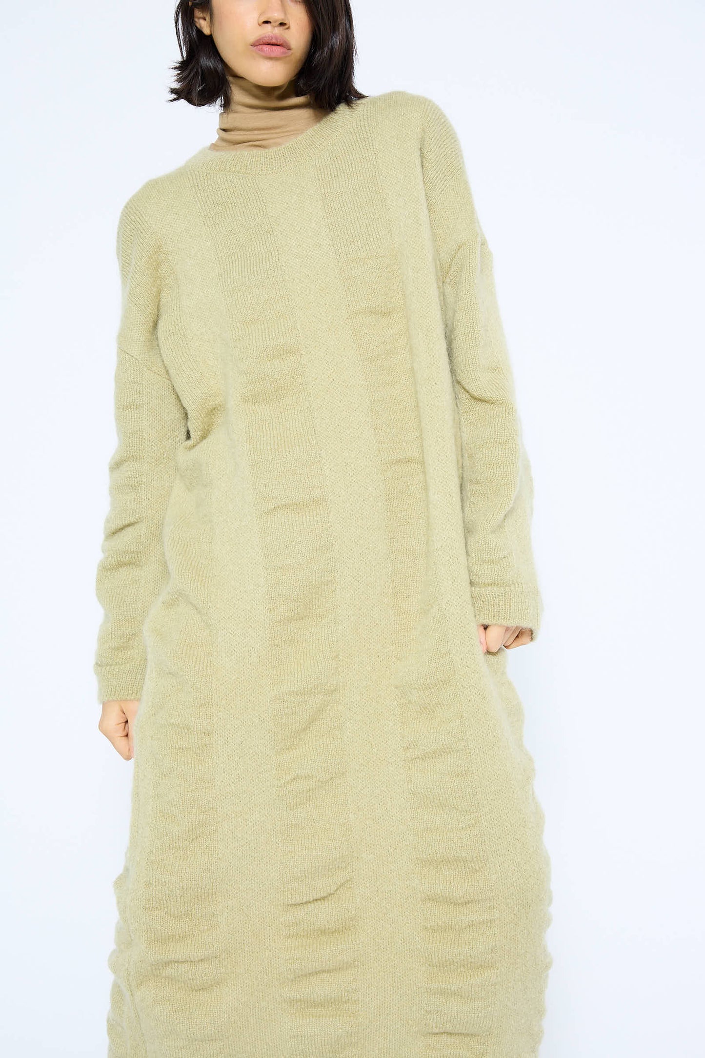 A person wearing a long, lime Mohair and Wool Waterfall Knit Dress by Black Crane stands against a plain white background. Only the bottom half of their face is visible.