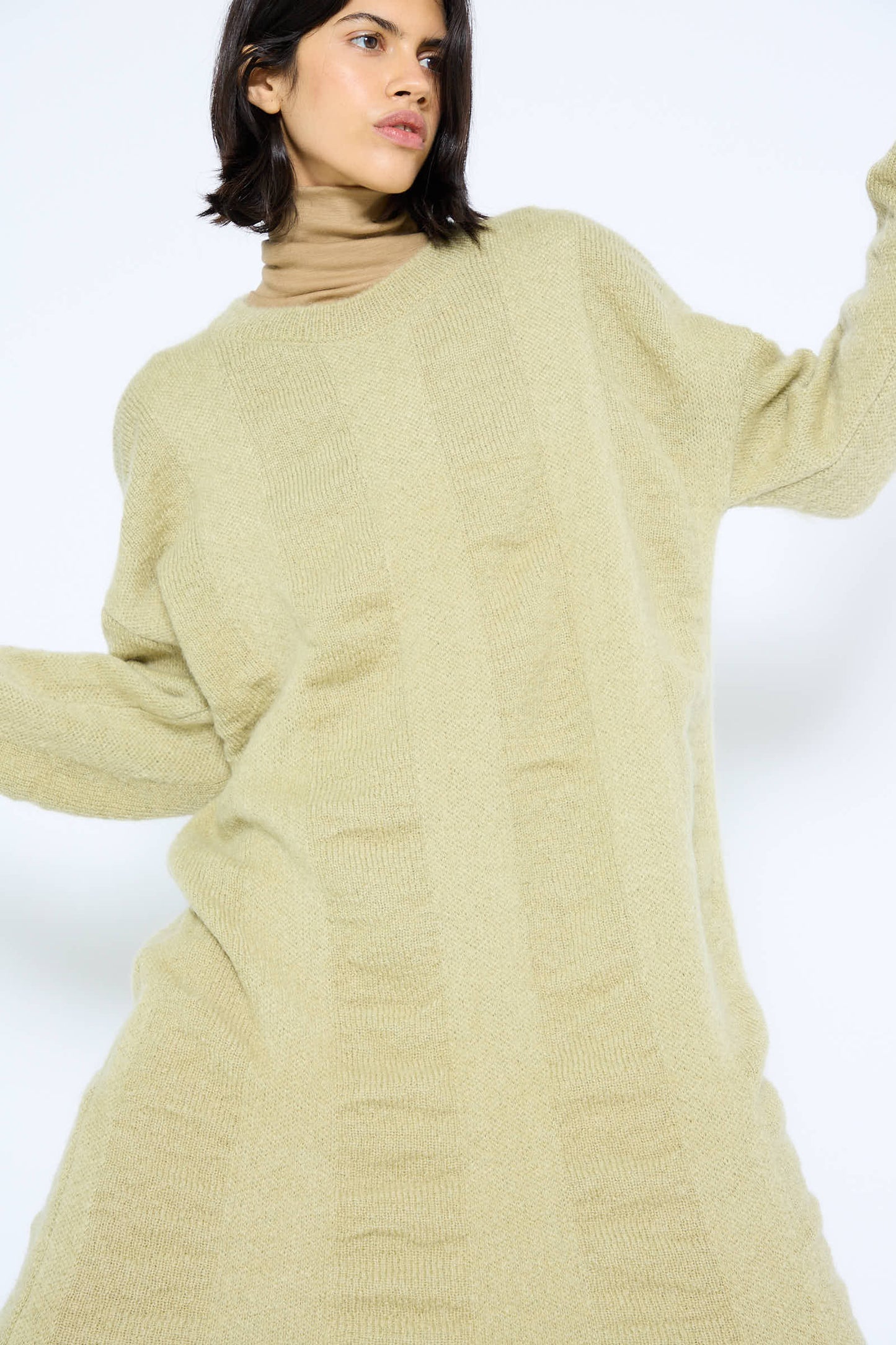 A person wearing a Mohair and Wool Waterfall Knit Dress in Lime by Black Crane, posing against a plain light background.