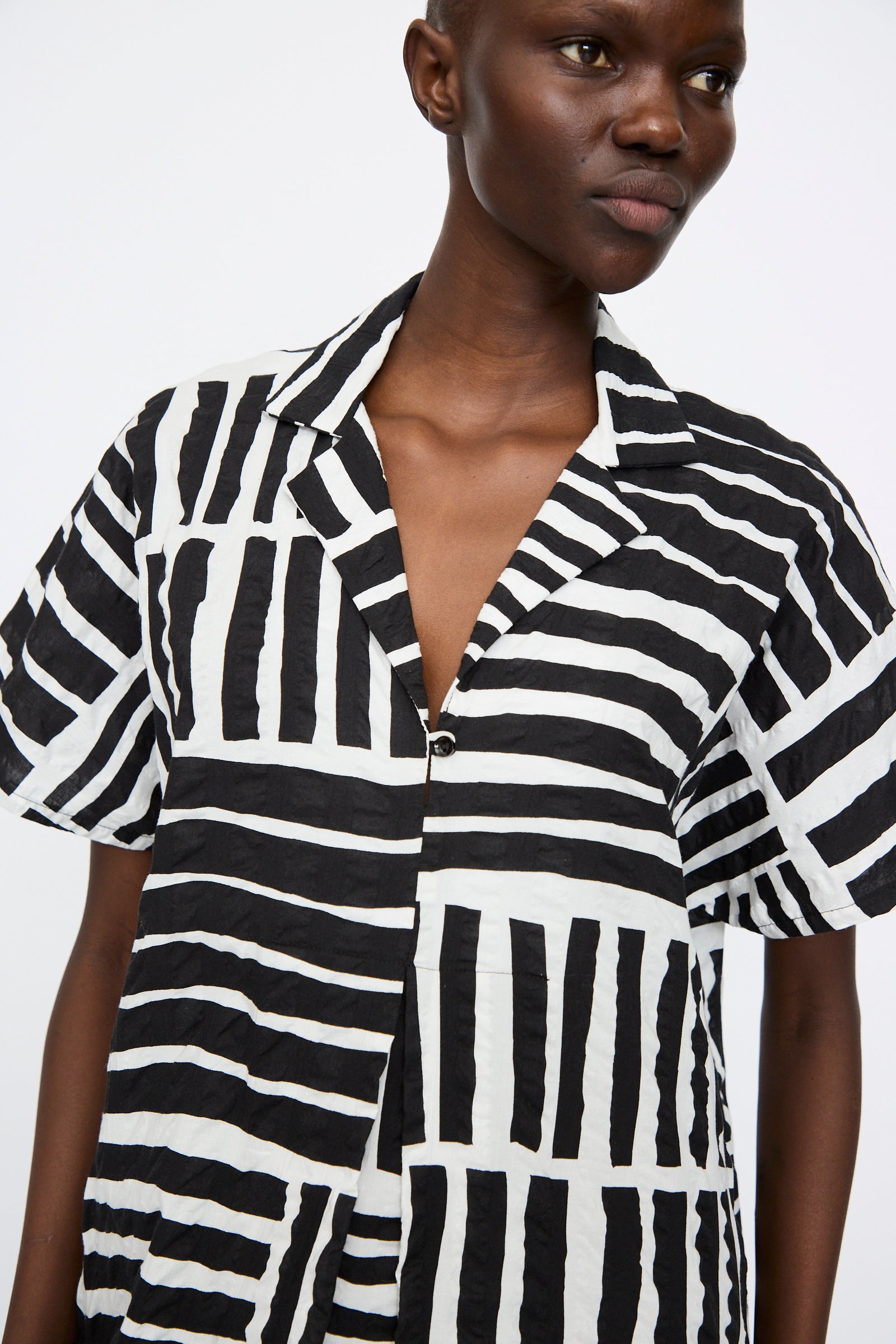 A person wearing the Black Crane Narrow Kite Dress in a black print stands against a plain white background.