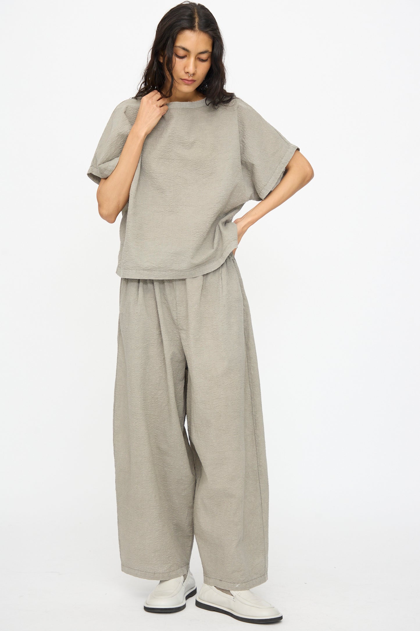A person wears the Black Crane Textured Cotton Boxed Top in Pale Grey with matching wide-leg pants and white shoes, standing against a plain white background.