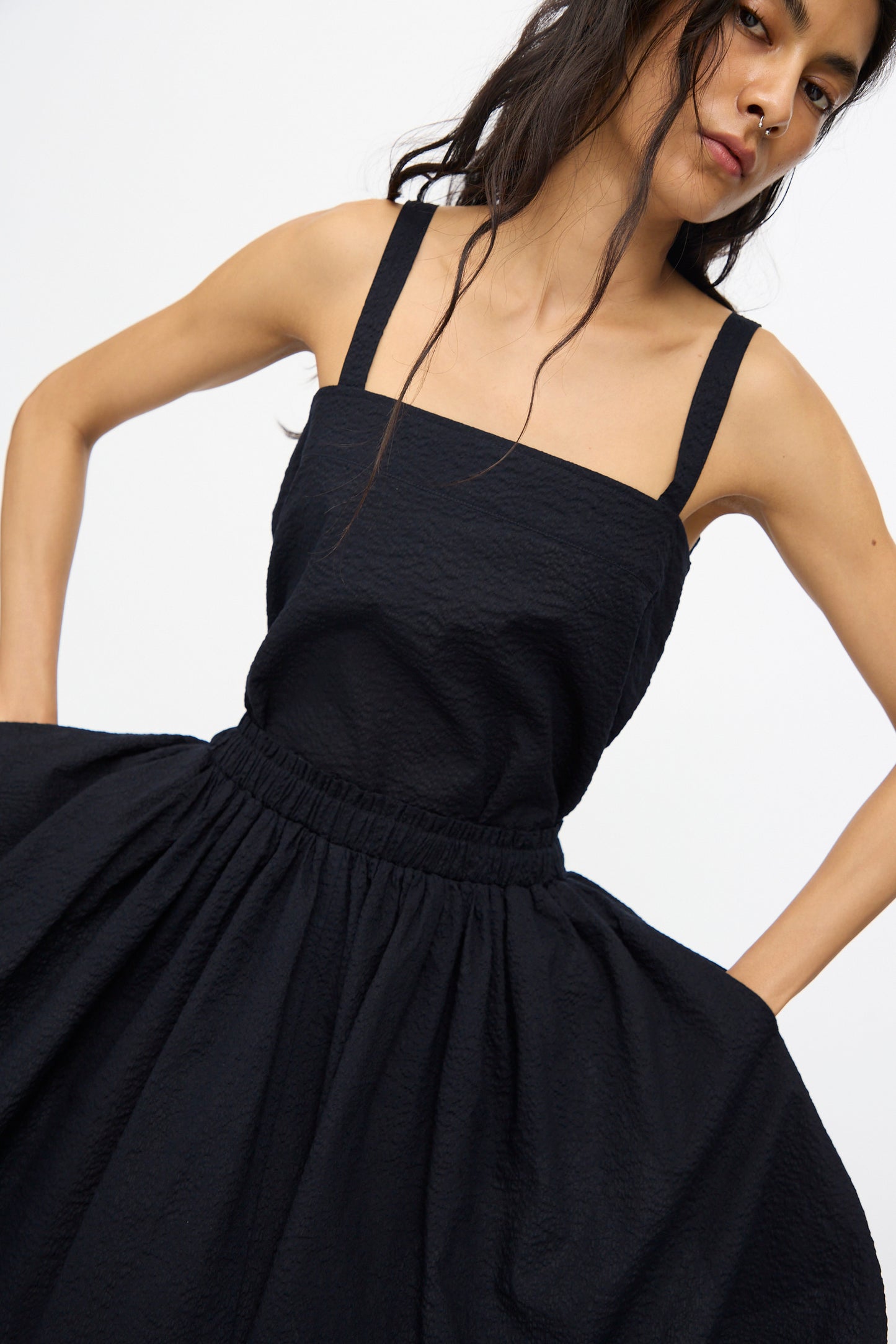 Woman wearing the Black Crane Textured Cotton Paper Skirt in Midnight, styled simply with hands on hips against a plain background.