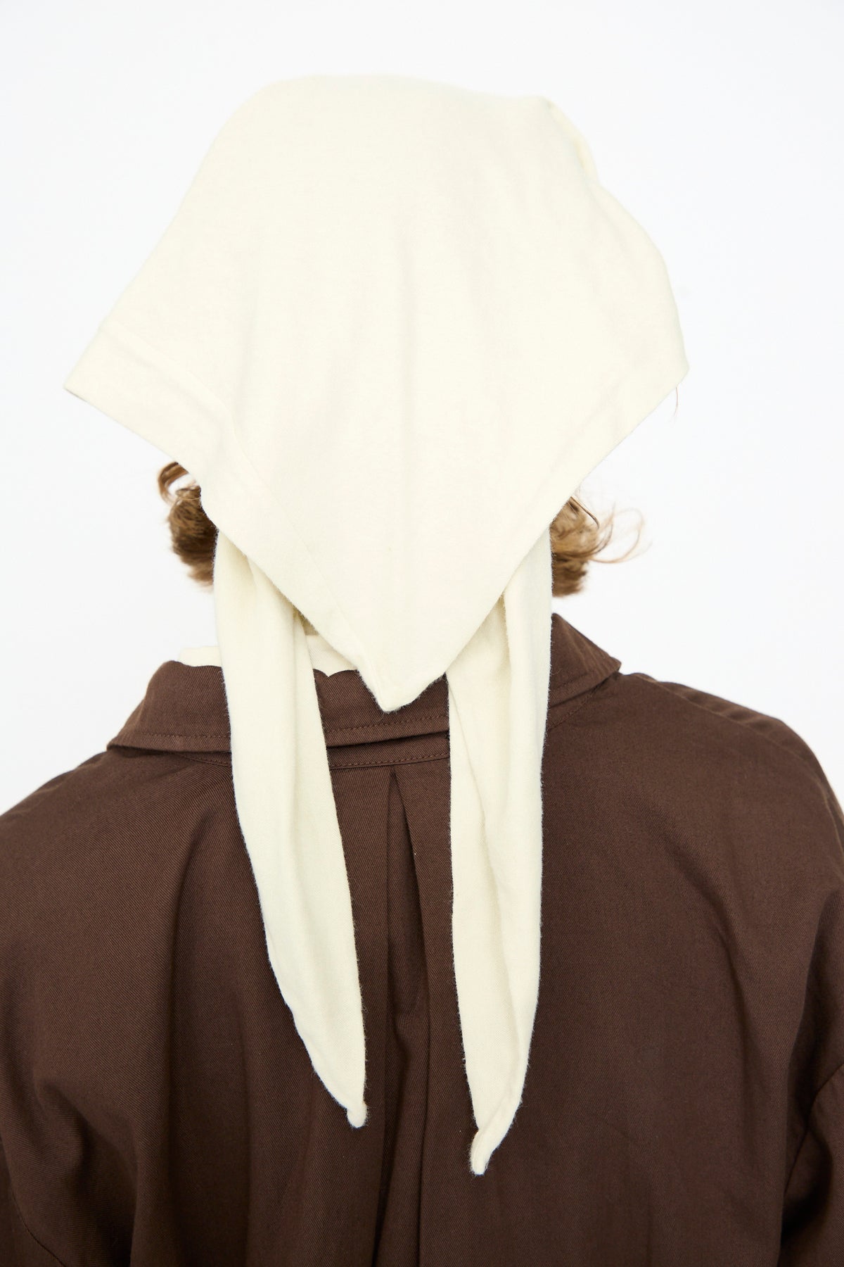 A person, shown from behind against a plain white background, wears a brown garment paired with the Black Crane Triangle Scarf in Natural, tied at the back.