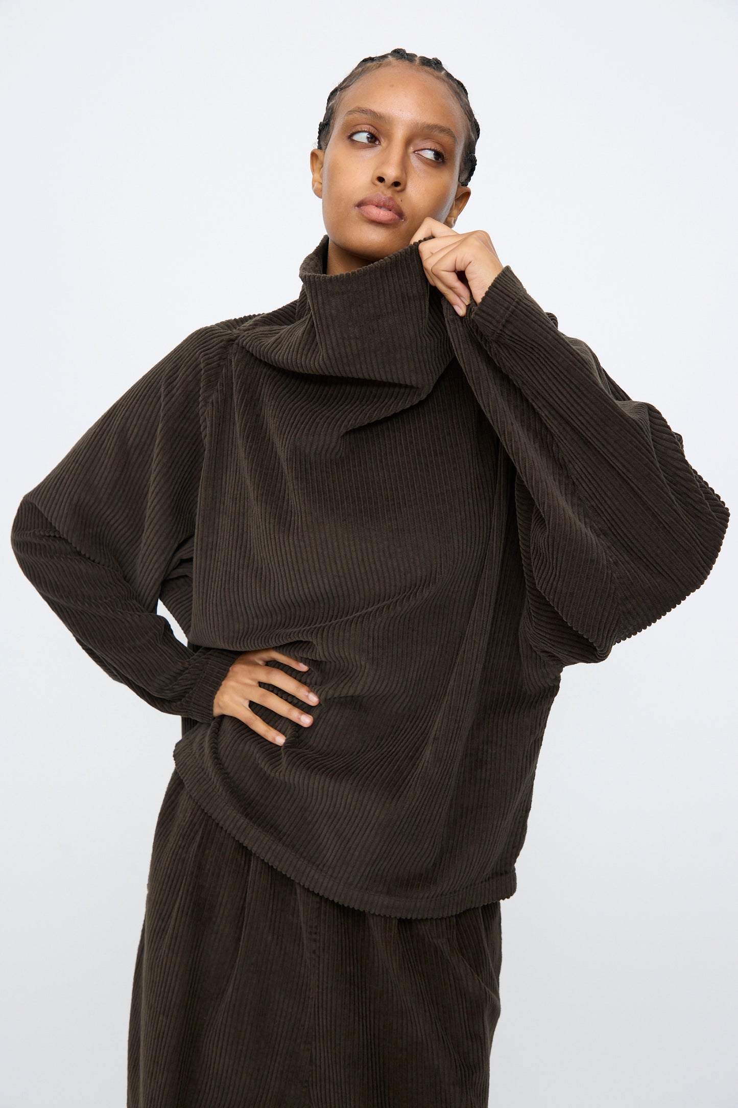 A person wears the Black Crane Tube Top in Forest, a relaxed-fit cotton top, standing against a plain light background.
