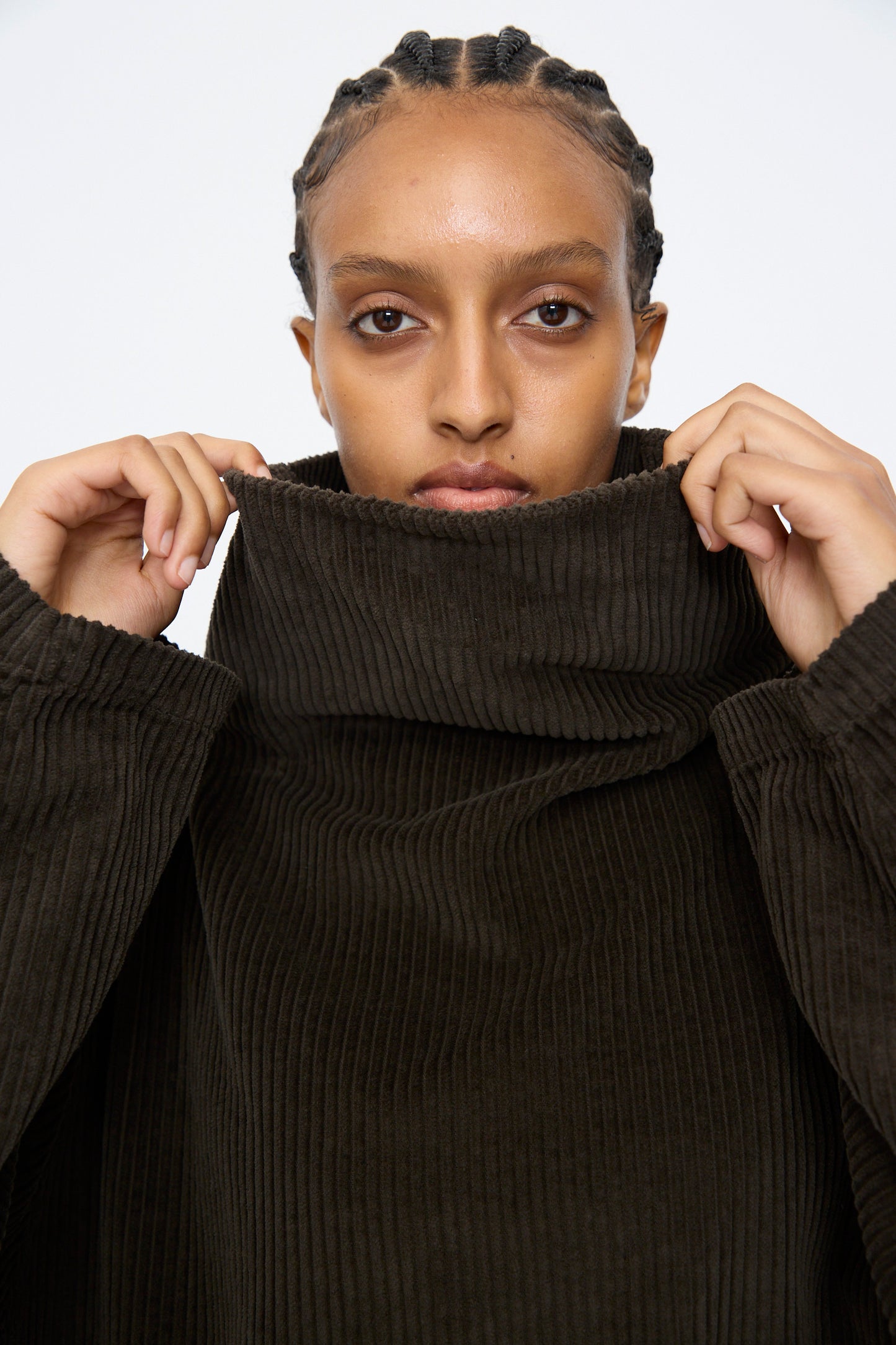 A person with braided hair looks at the camera while wearing the Black Crane Tube Top in Forest.