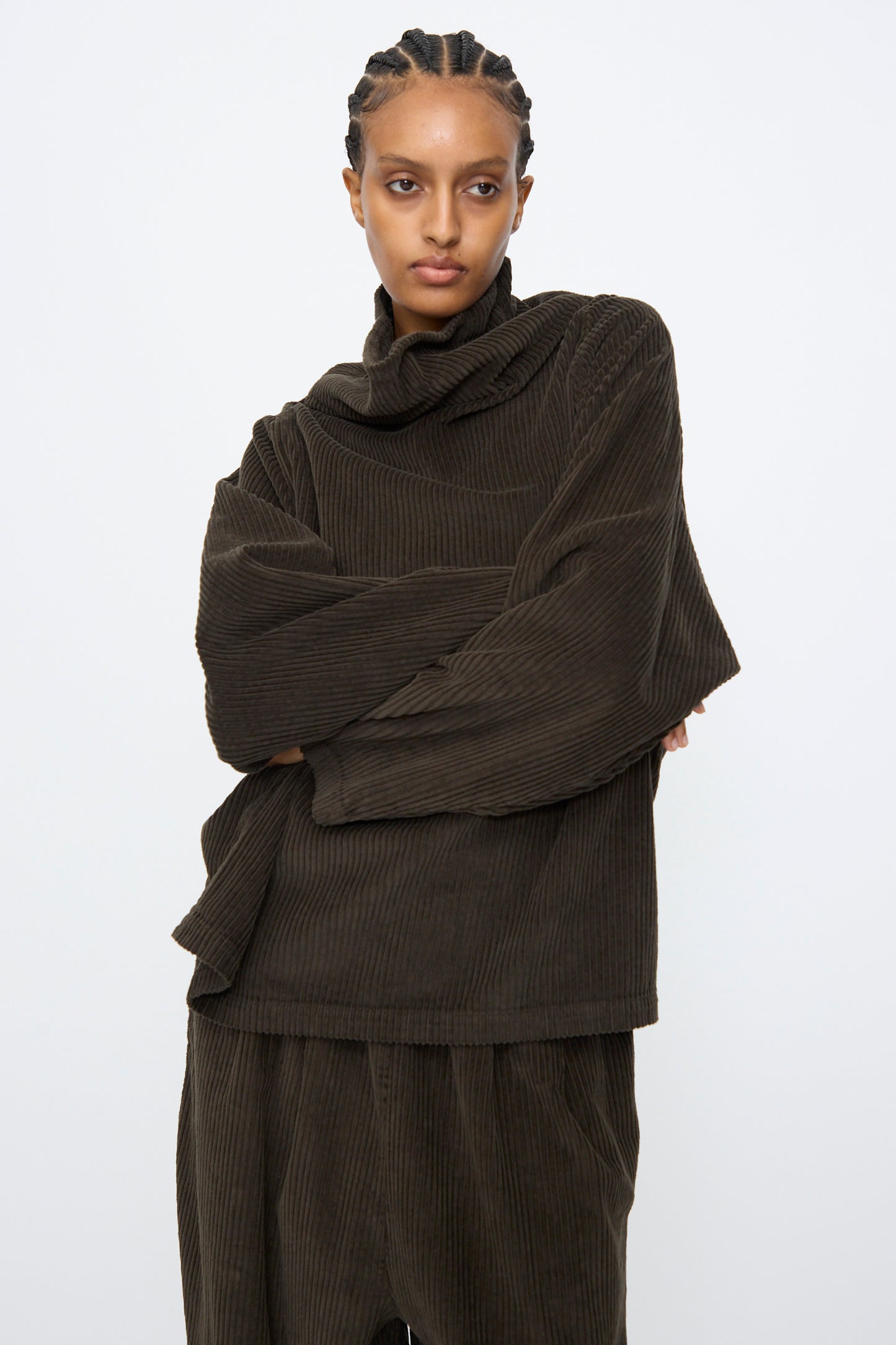 A person wearing the Black Crane Tube Top in Forest and matching pants poses with arms crossed against a plain white background.
