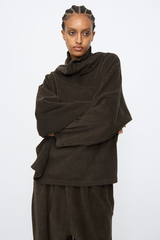 A person wearing the Black Crane Tube Top in Forest and matching pants poses with arms crossed against a plain white background.