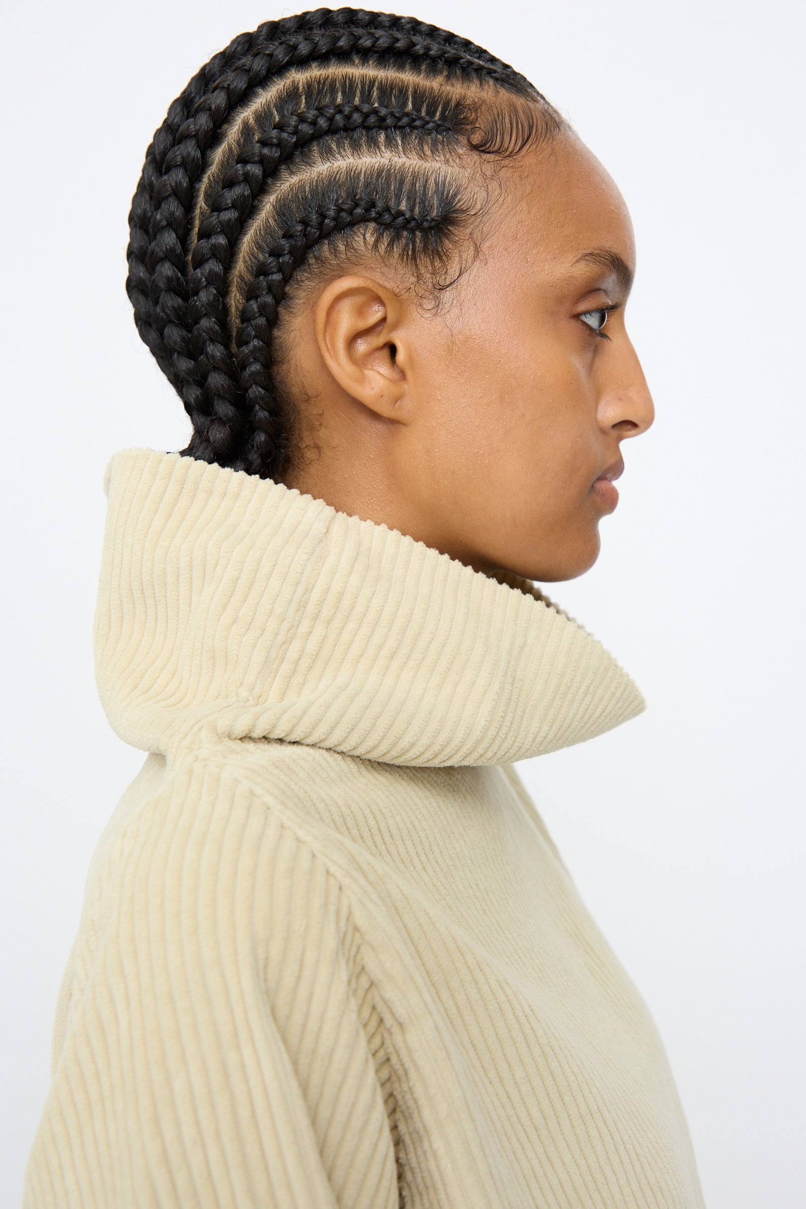 A person in profile, with neatly braided cornrows, wears the Black Crane Tube Top in Ivory against a plain background.