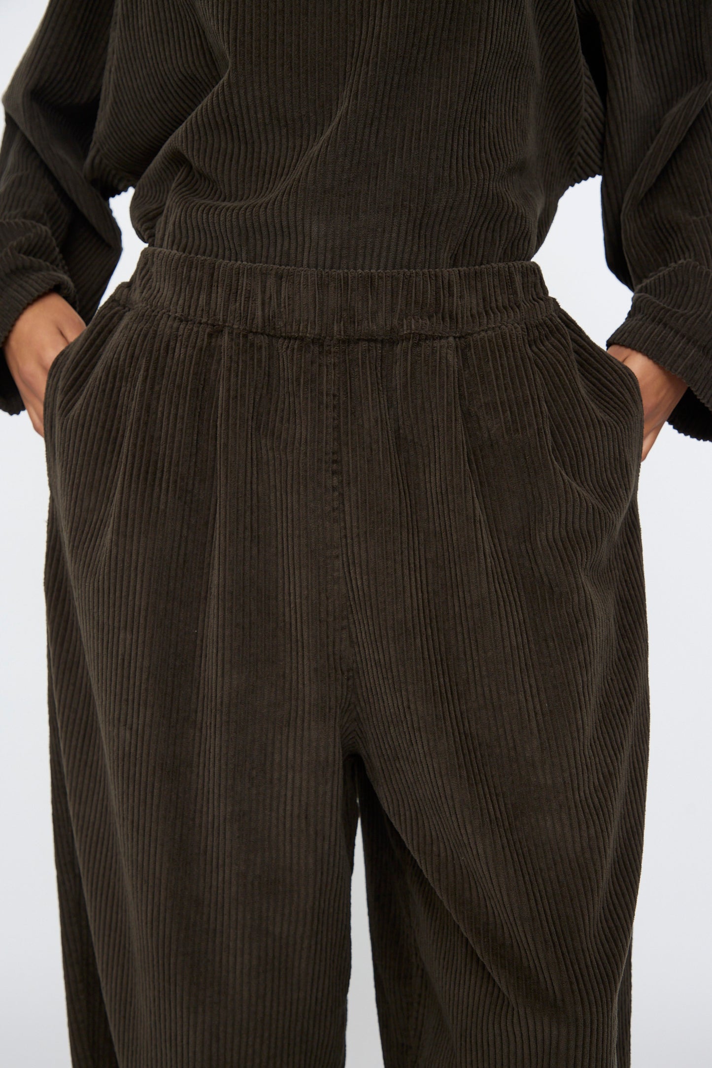 Model wearing Black Crane's Wide Pants in Forest—wide-leg corduroy style with an elastic waistband and side pockets, paired with a matching top. Made in the USA.