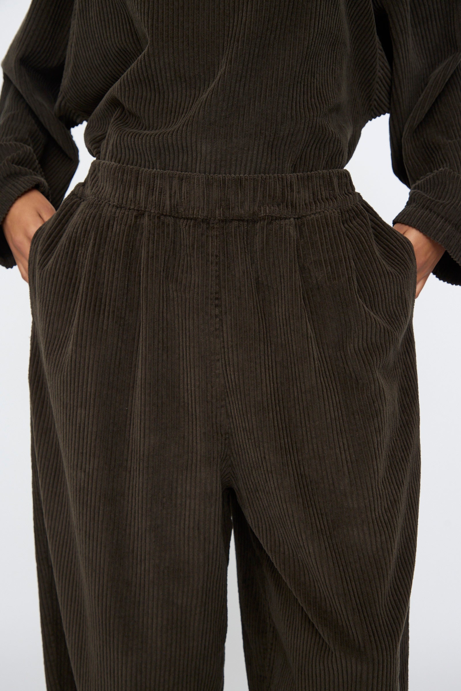 Model wearing Black Crane's Wide Pants in Forest—wide-leg corduroy style with an elastic waistband and side pockets, paired with a matching top. Made in the USA.