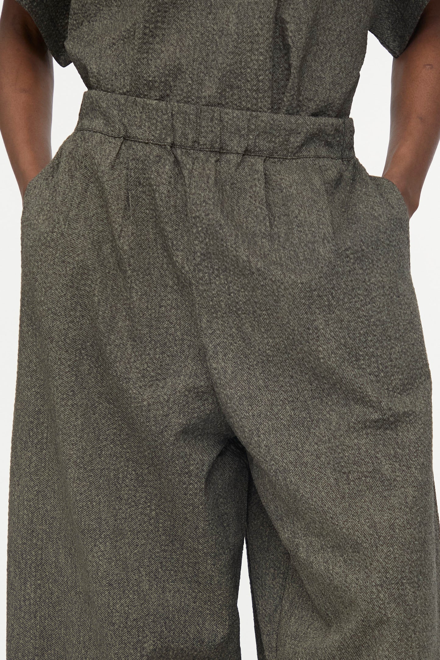 Close-up of a person wearing Black Crane's Wide Pants with Micro Wave Texture in Steel, hands in pockets.