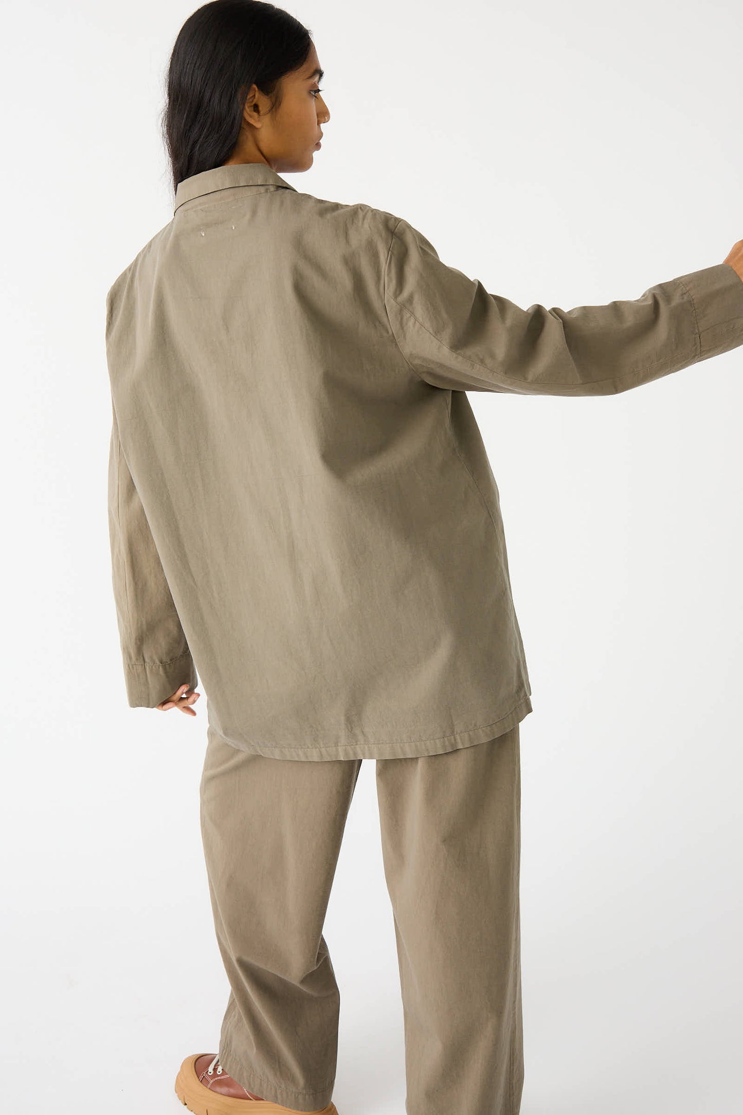 Person wearing a Woven Cotton Blazer in Dark Olive by Black Crane, turned slightly away from the camera against a plain white background.