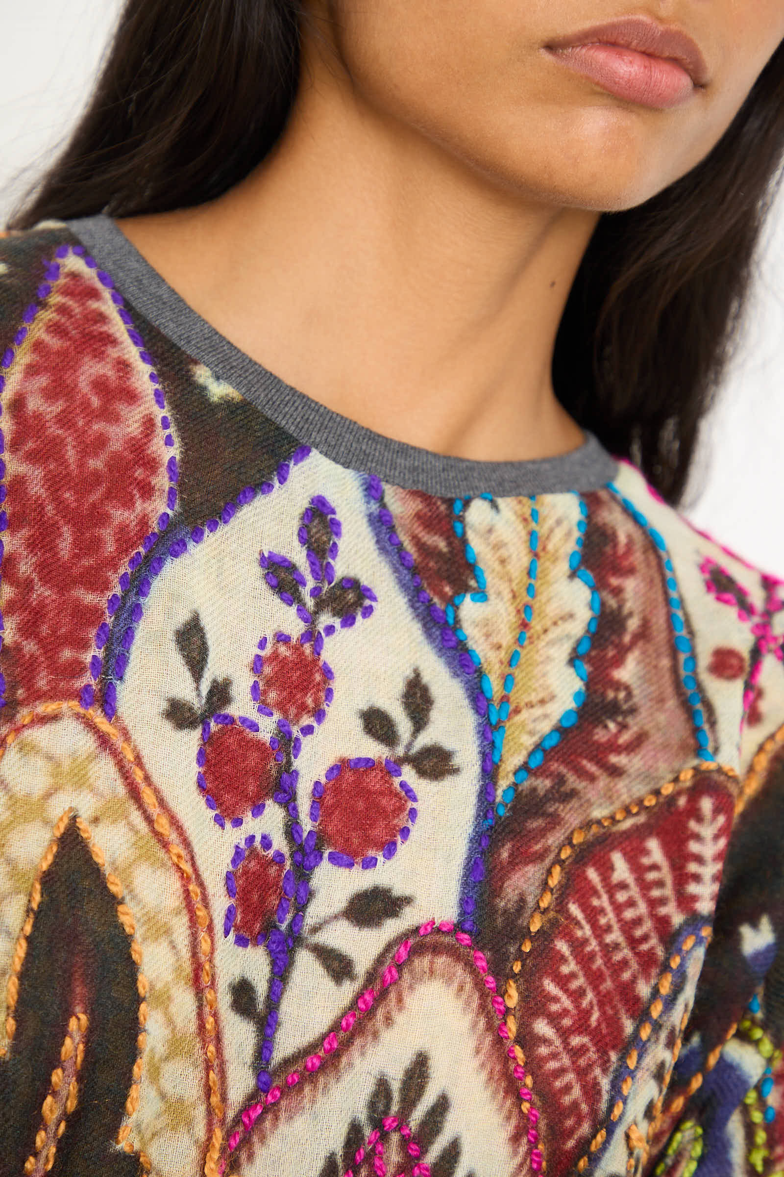 A close-up of a person wearing the Bless Embroidered Wool No. 78 Sweater in Multicolor Brown, showcasing its vibrant floral motif embroidery and abstract patterns.