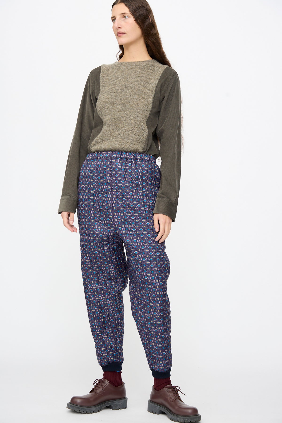 A person wears a long-sleeved two-tone top and dark blue floral No. 08 Monpe Pants in Floral Print II styled with brown lace-up shoes.