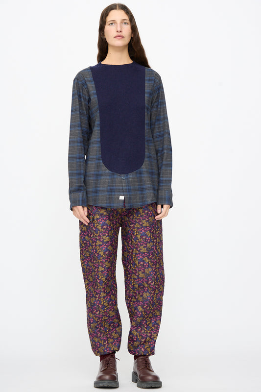A model wears a navy and plaid long-sleeve top, Bless No. 08 Monpe Pants in Floral Print III, and dark brown lace-up boots.