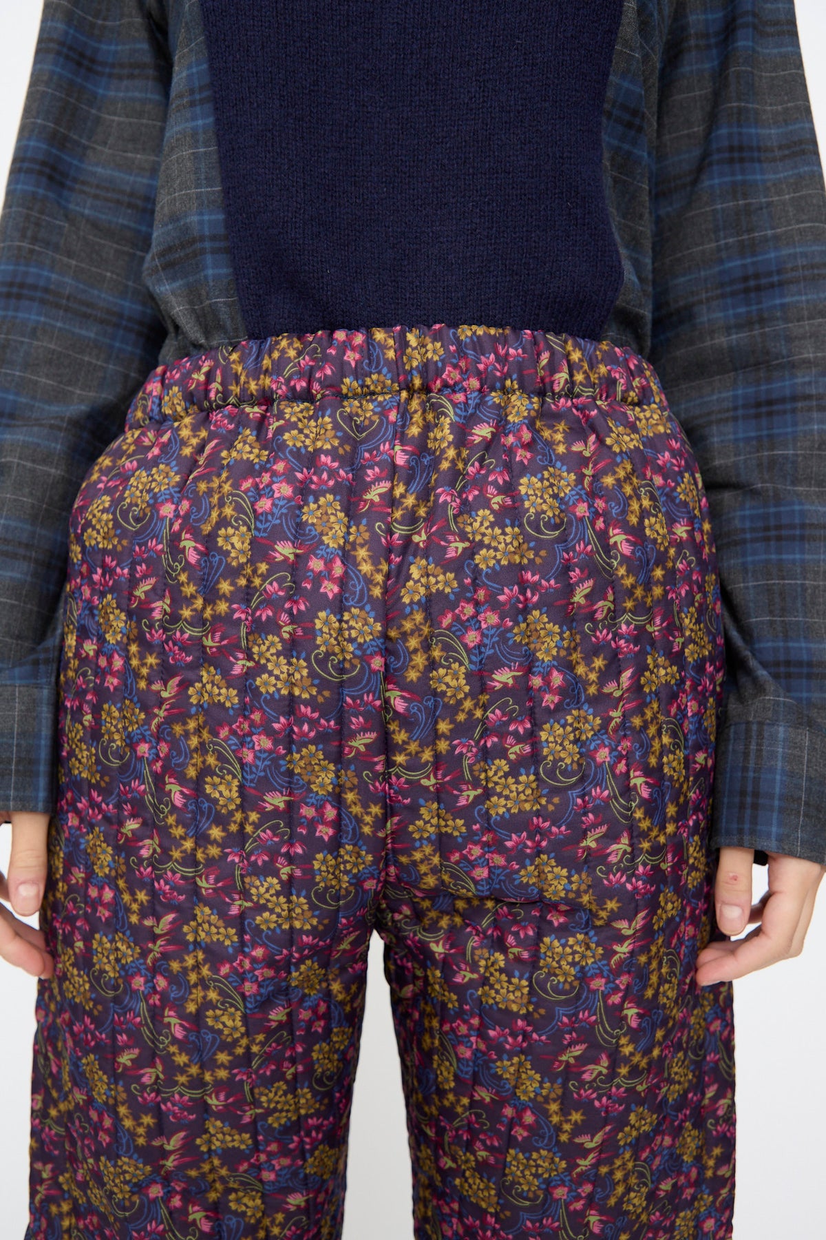 Bless No. 08 Monpe Pants in Floral Print III: quilted dark purple floral pants with an elastic waist, worn with a dark blue plaid shirt.