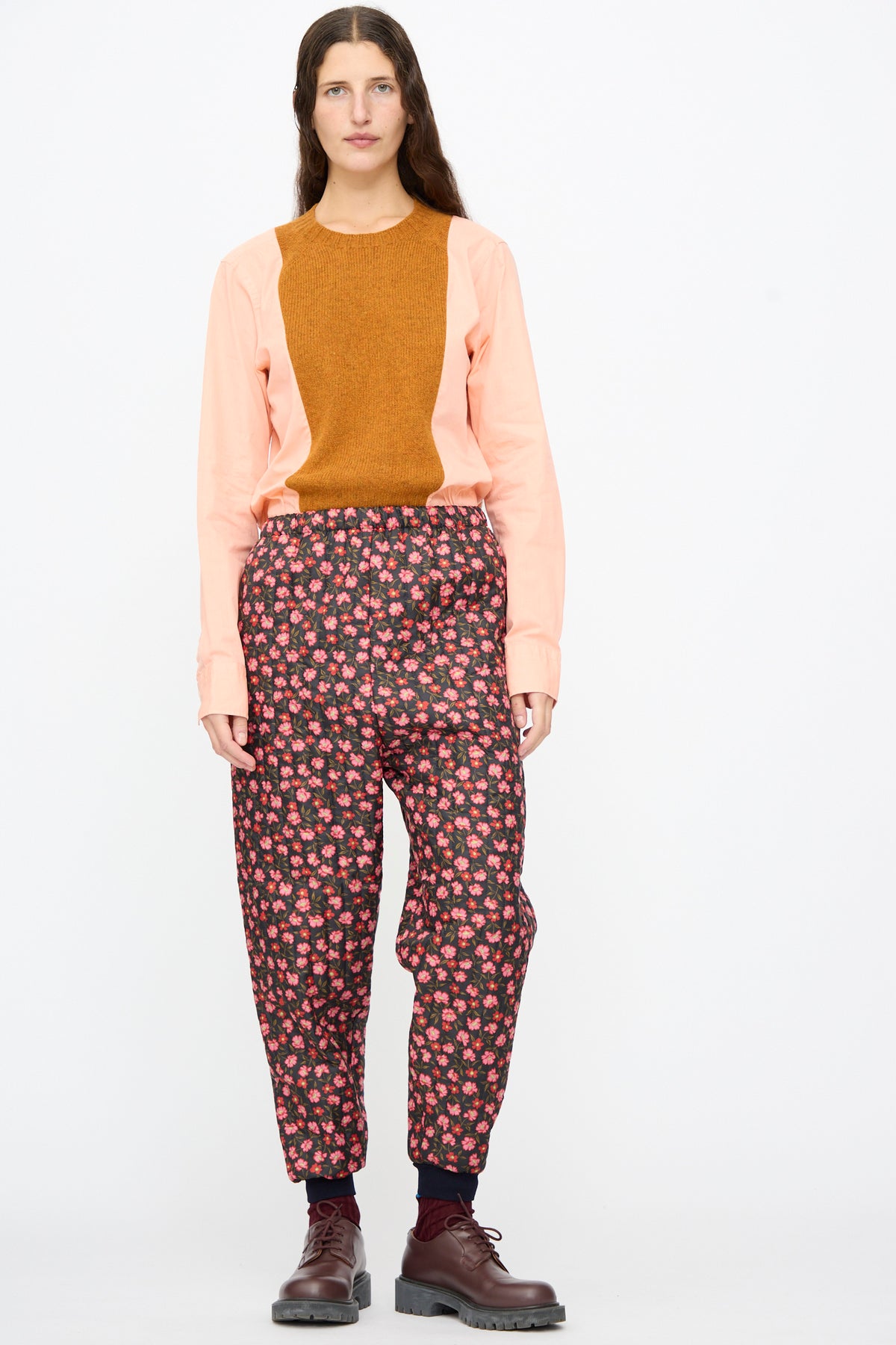 A person wearing a peach and brown long-sleeved shirt, Bless No. 08 Monpe Pants in Floral Print V, and brown lace-up shoes.