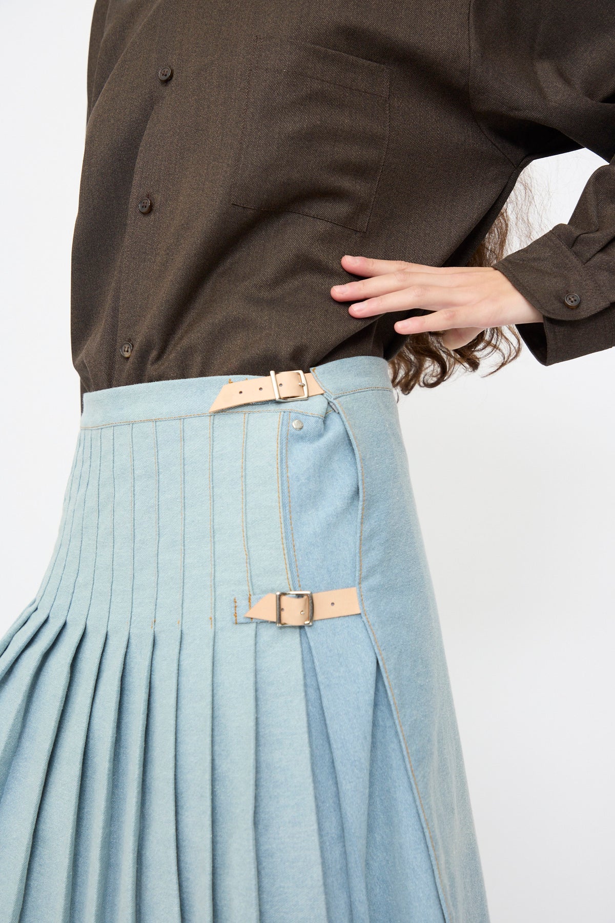 Bless No. 52 Denimkilt in Denim Light Blue, a pleated midi skirt featuring two beige leather buckle straps at the side.
