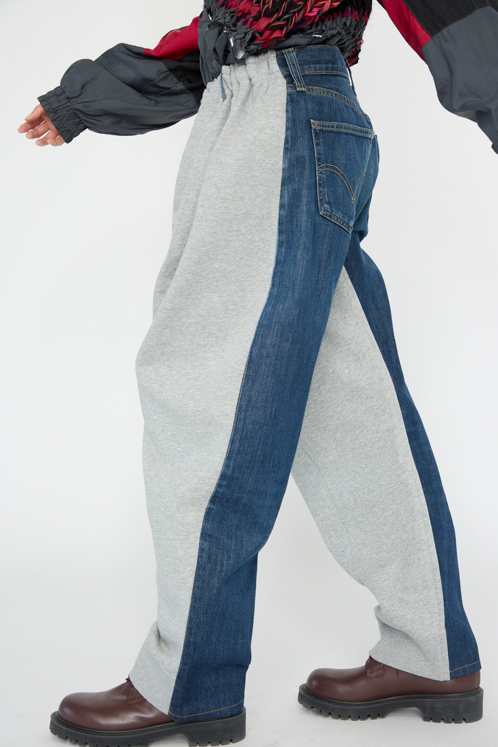 A person walks to the side, wearing Bless's No. 61 Overjoggingjeans in Lightgrey and Denimblue paired with brown shoes.