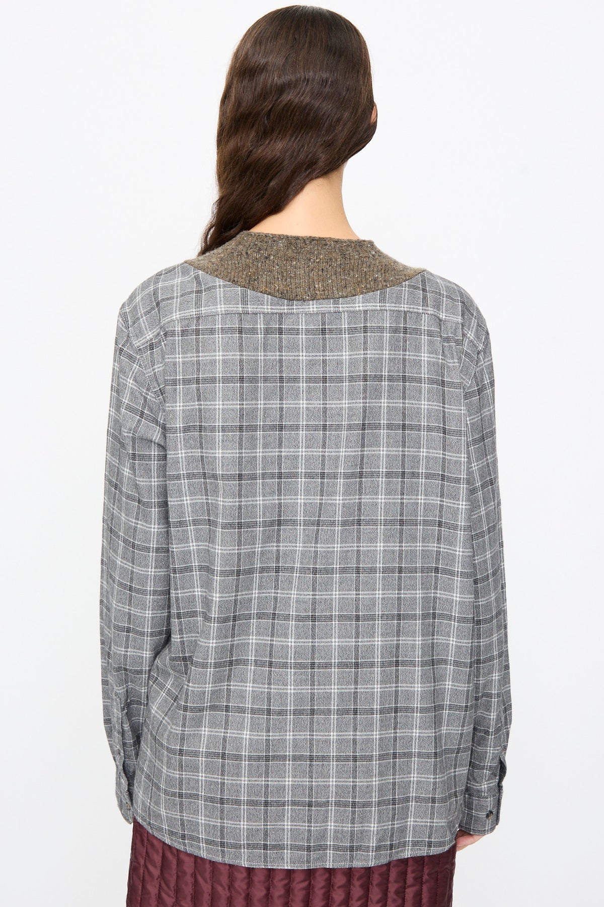 A person seen from behind wears a Bless No. 68 Frontinsertpullover in Unique I, a relaxed-fit grey plaid flannel pullover with a brown knitted collar and a dark red quilted hem.