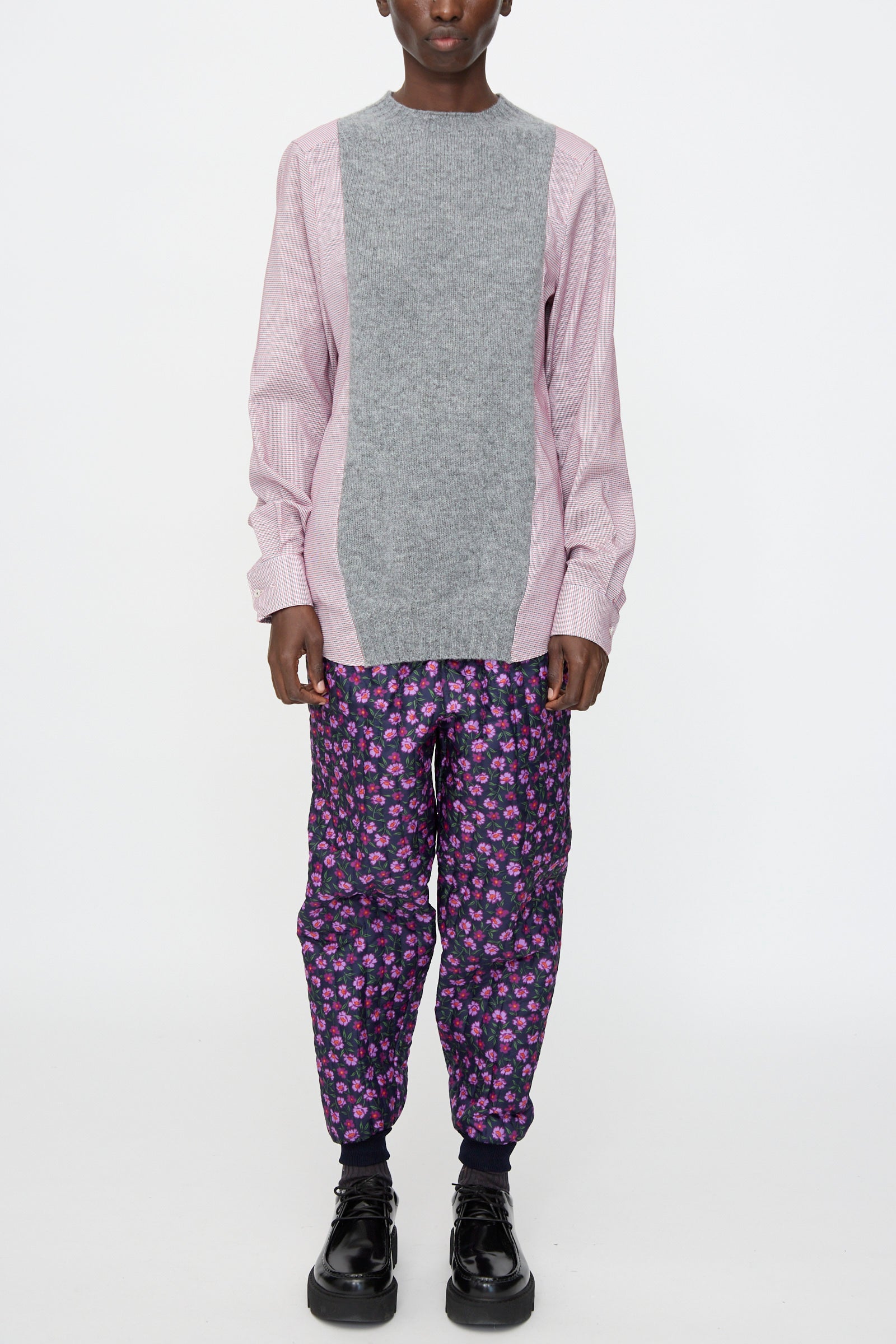 A person stands against a white background wearing the Bless No. 68 Frontinsertpullover in Unique I, purple floral-patterned pants, and black shoes.