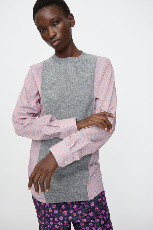 A person wears the Bless No. 68 Frontinsertpullover in Unique I, featuring a cotton poplin shirt with shetland wool panel and pink striped sleeves, paired with purple floral pants, standing against a plain white background.