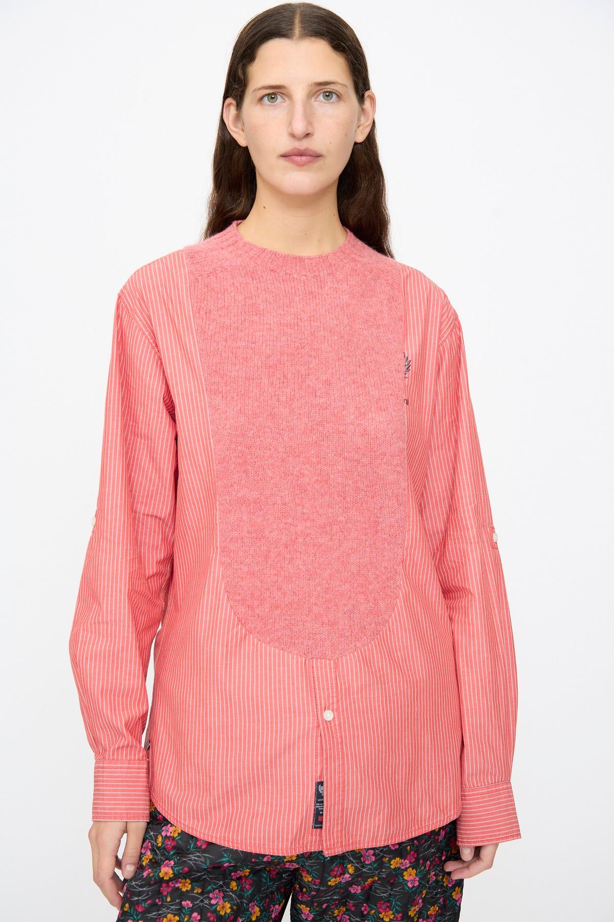 A person wears a Bless No. 68 Frontinsertpullover in Unique II, a pink pinstriped poplin pullover featuring a large, solid-pink knit panel integrated into the front.