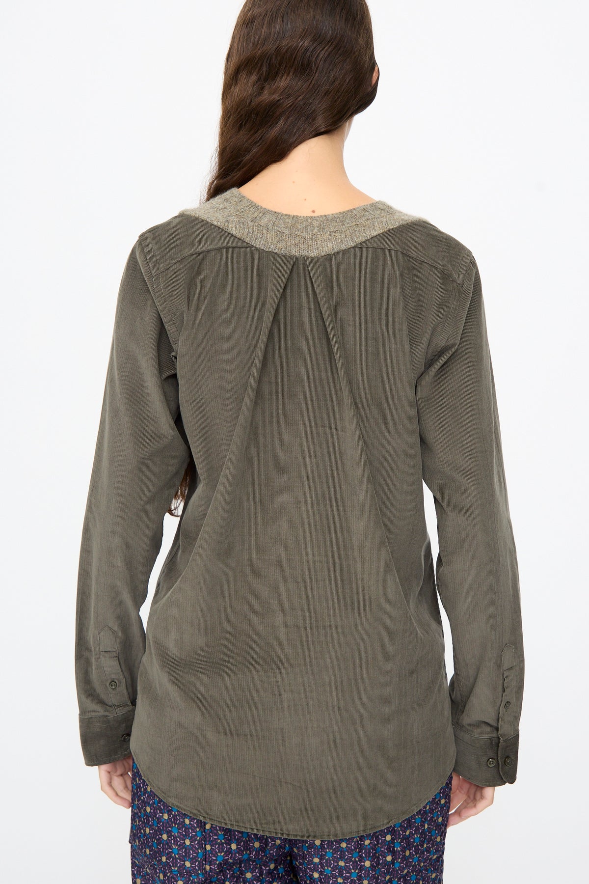 Back view of a person wearing a Bless No. 68 Frontinsertpullover in Unique III, an olive green corduroy pullover with a ribbed neckline and a pleated back yoke.