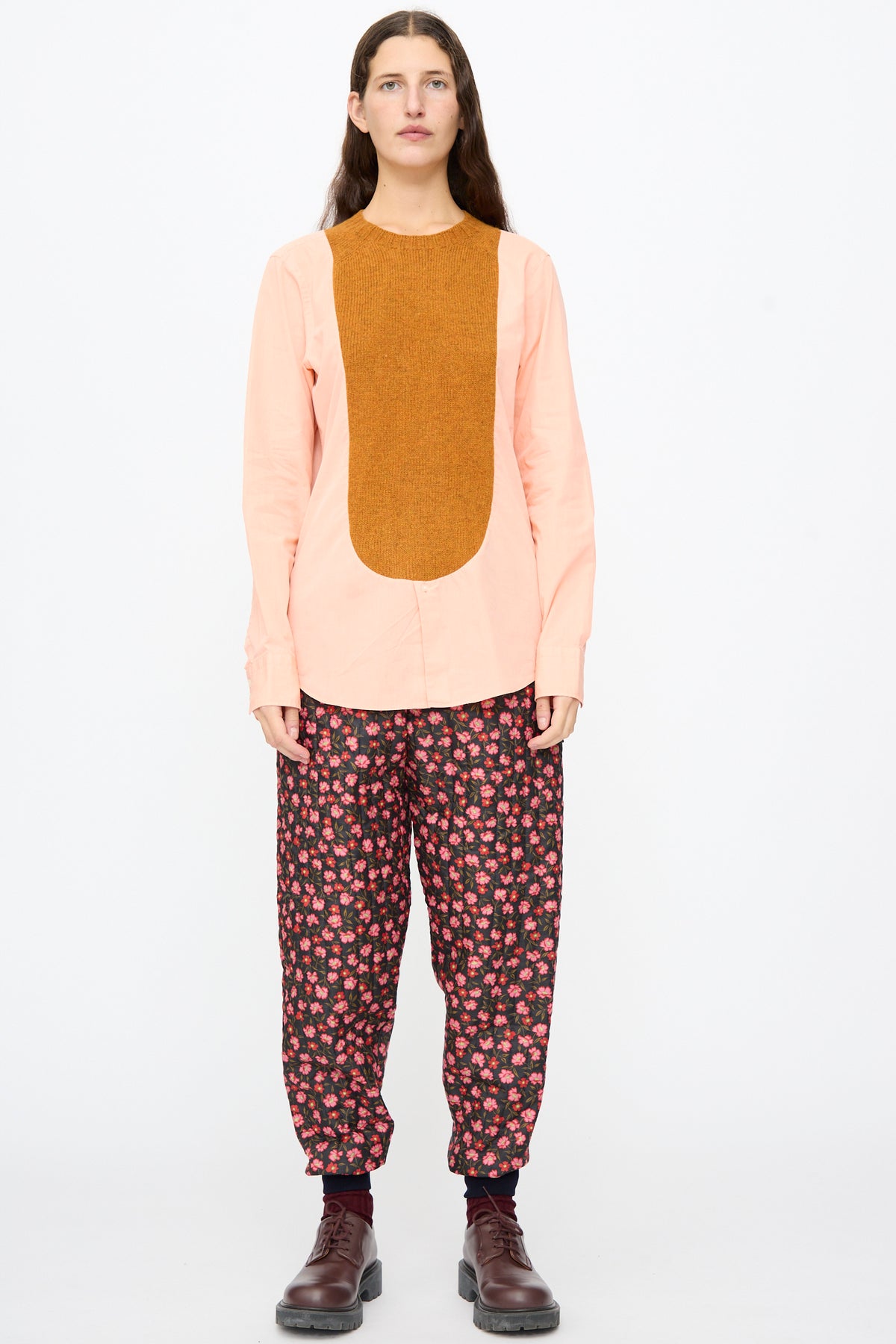 Bless No. 68 Frontinsertpullover in Unique V, a light pink button-up shirt with a large, vertical Shetland wool knit panel, worn with dark floral print trousers and brown leather shoes.